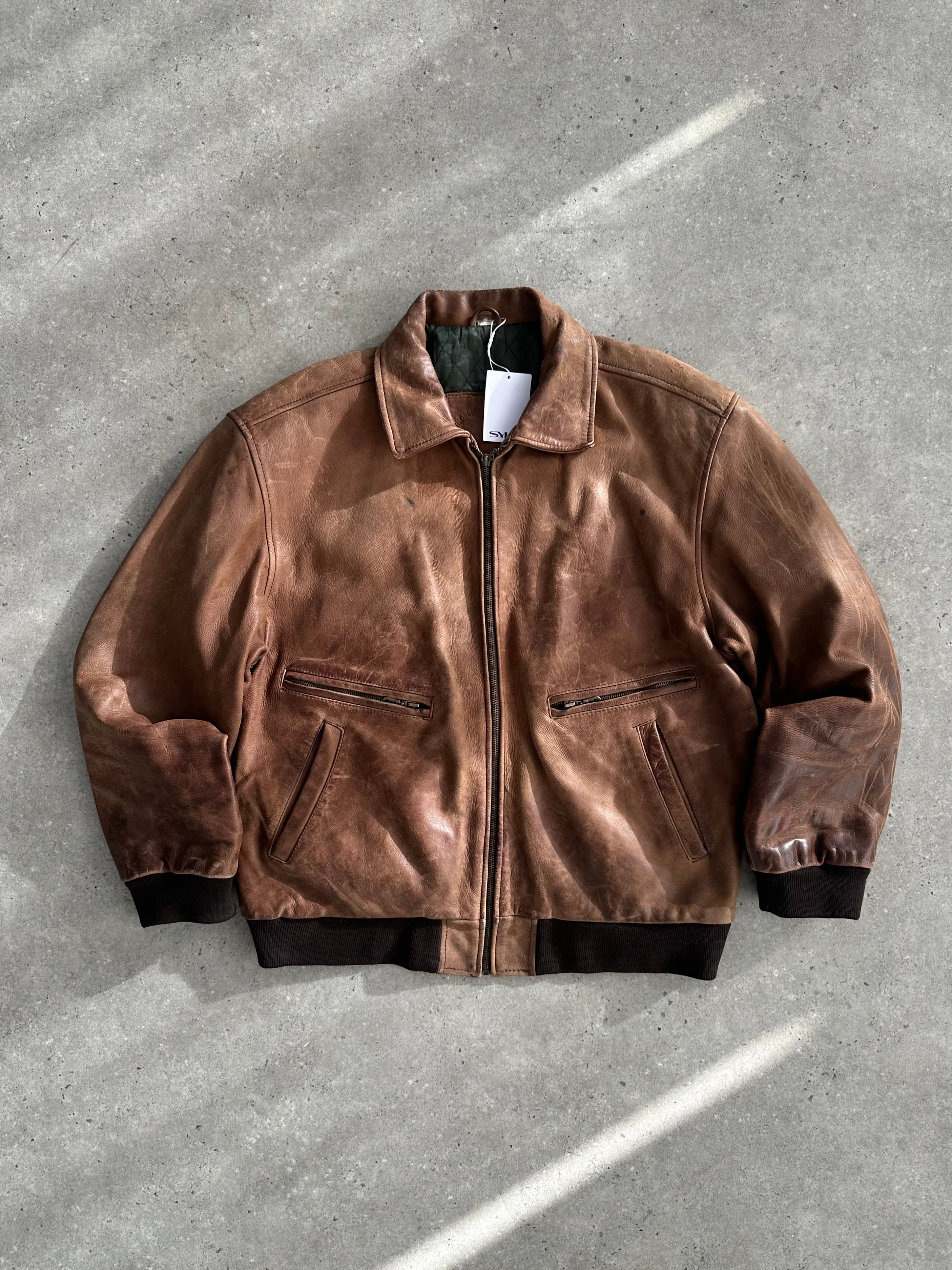 Vintage distressed leather bomber jacket in XL size, featuring rugged texture and classic design, displayed on a hanger.