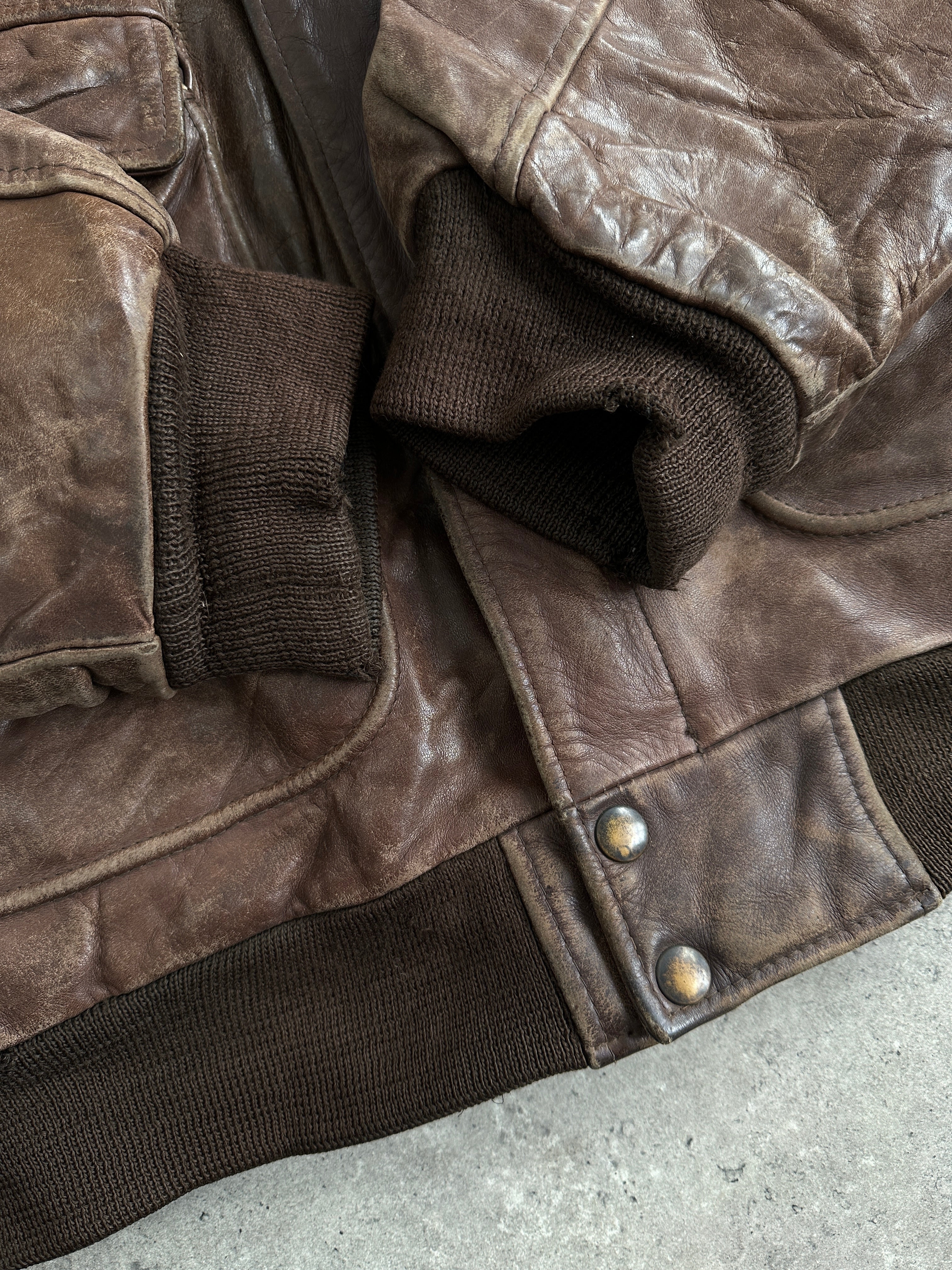 Vintage distressed leather bomber jacket in size XL, featuring rugged design and classic style, displayed on a hanger.