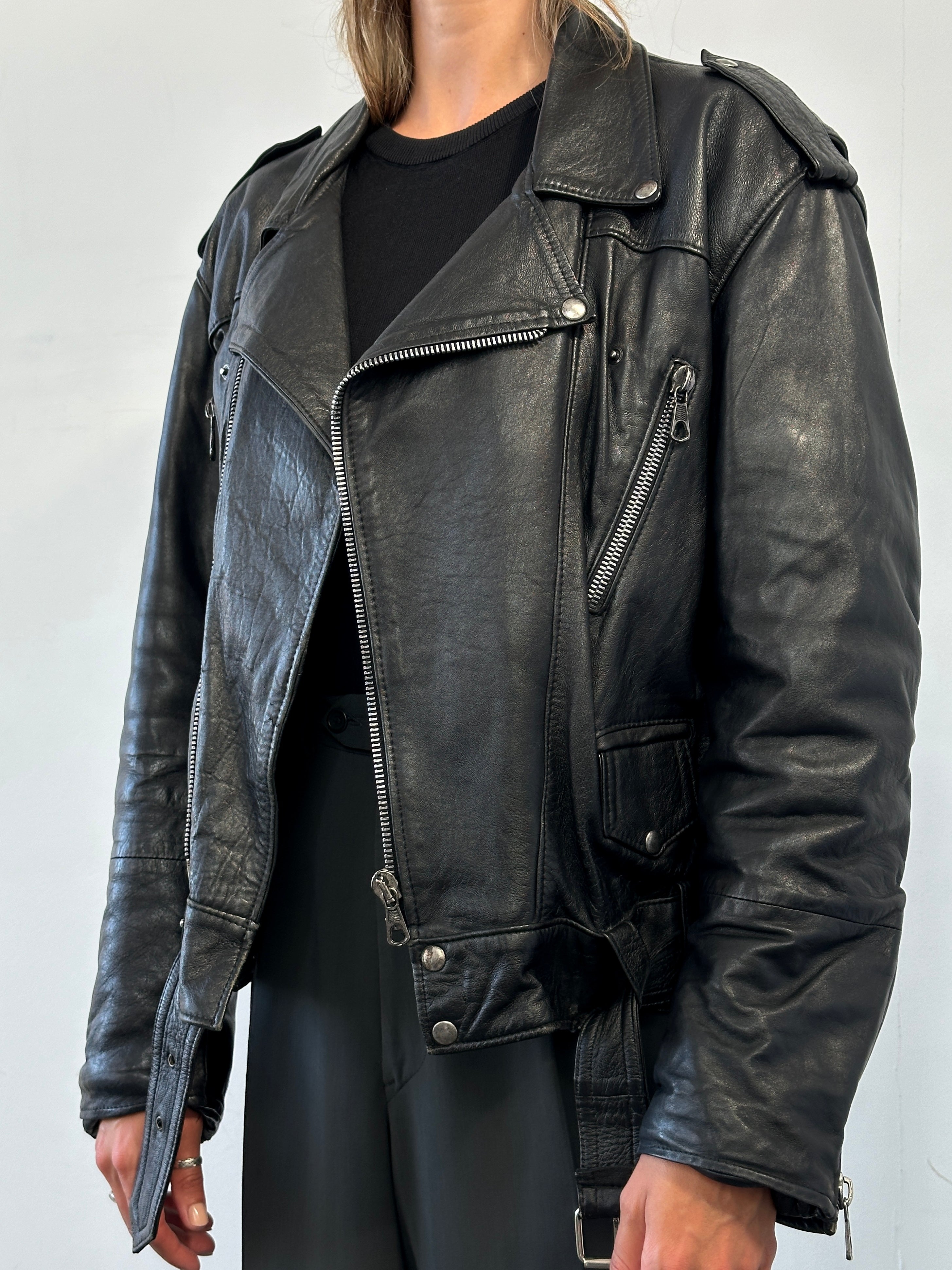 Vintage leather biker jacket in size M/L, featuring classic design, distressed leather, and metal hardware.
