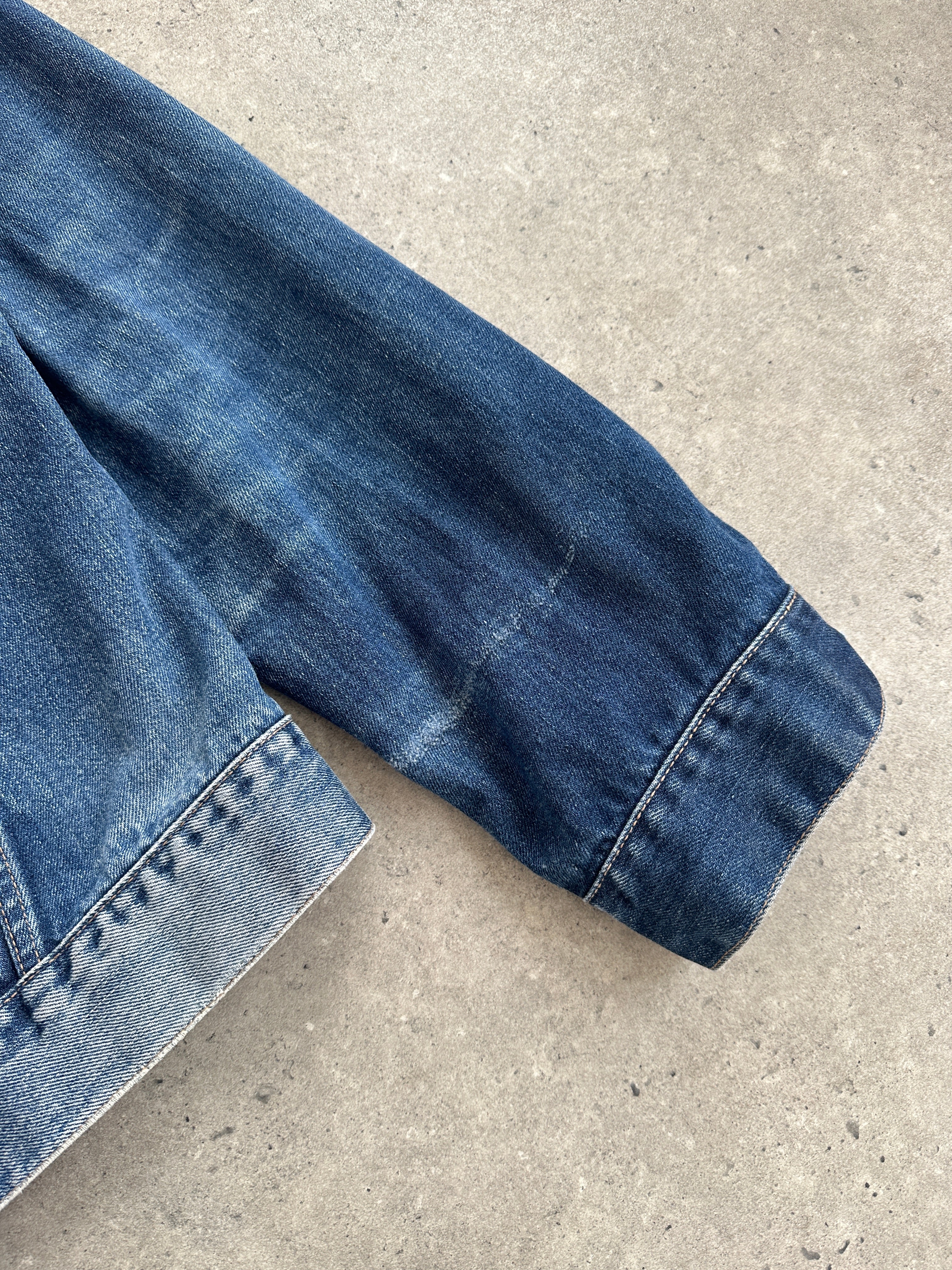 Levi’s faded denim jacket in size L displayed on a hanger, featuring classic stitching and distressed denim texture.