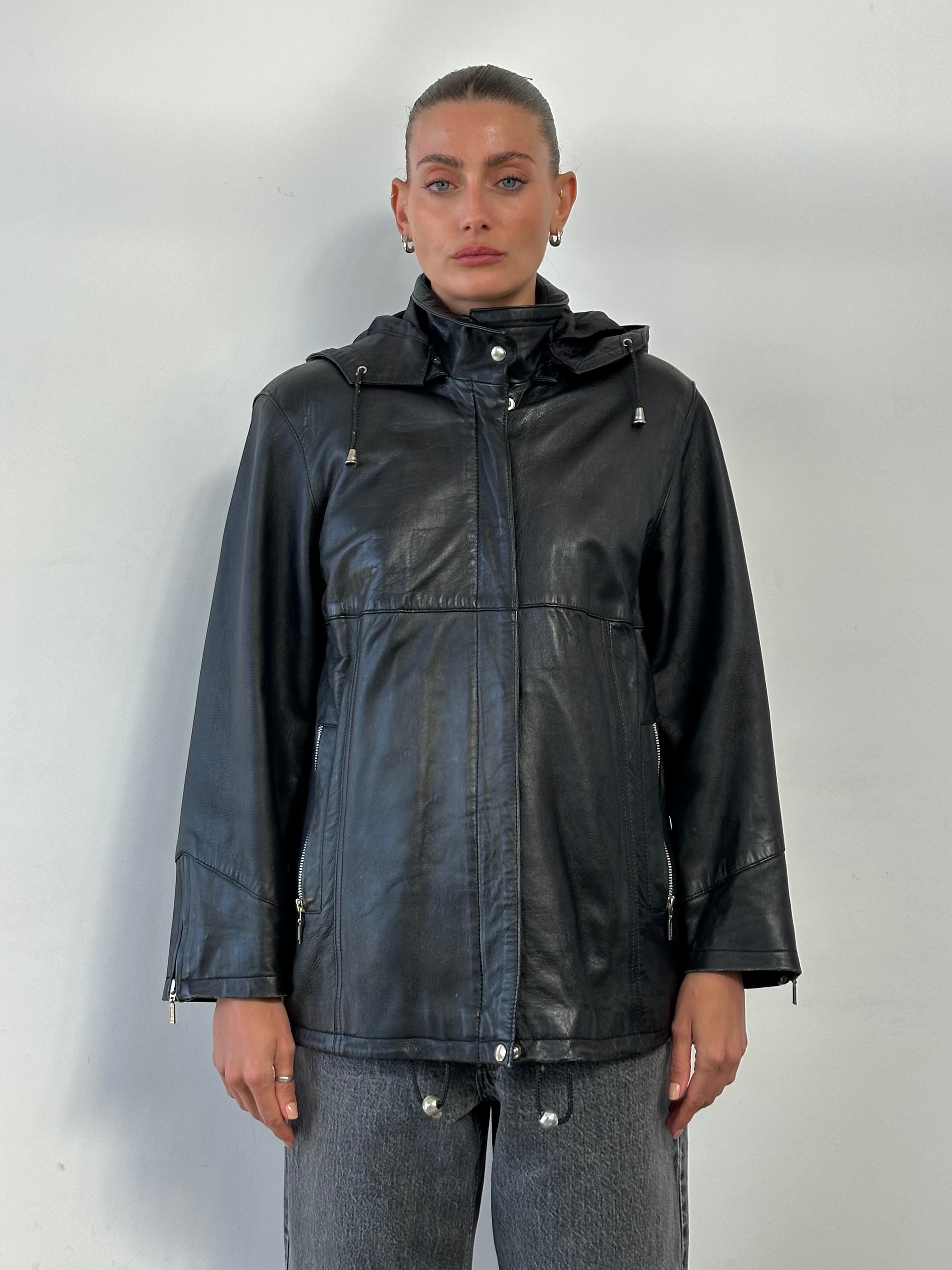 Vintage high neck leather jacket with removable hood, styled in black, featuring a fitted design and metal zipper details.
