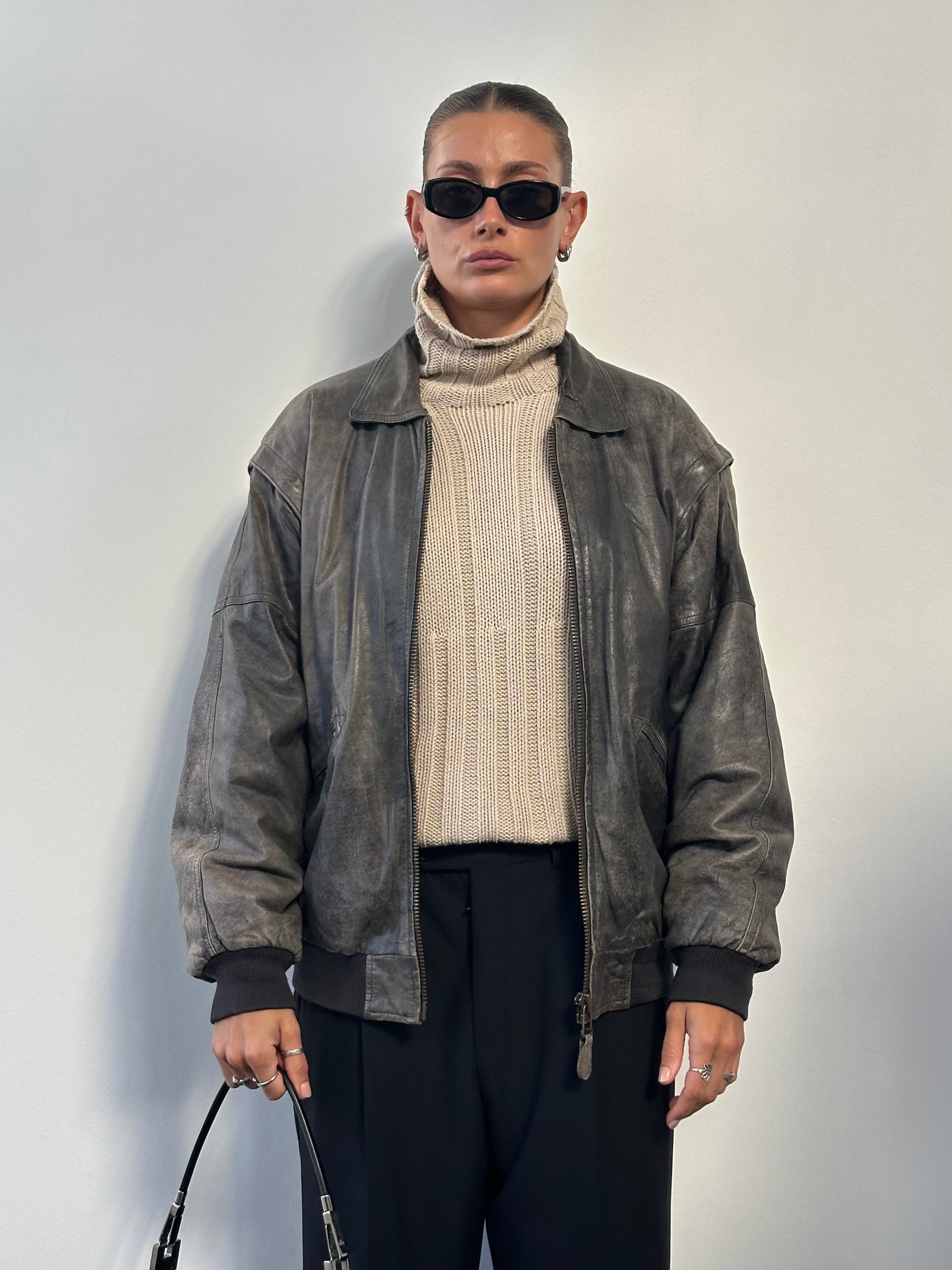 Vintage distressed leather bomber jacket in size L/XL, featuring rugged texture and classic design, showcased on a hanger.