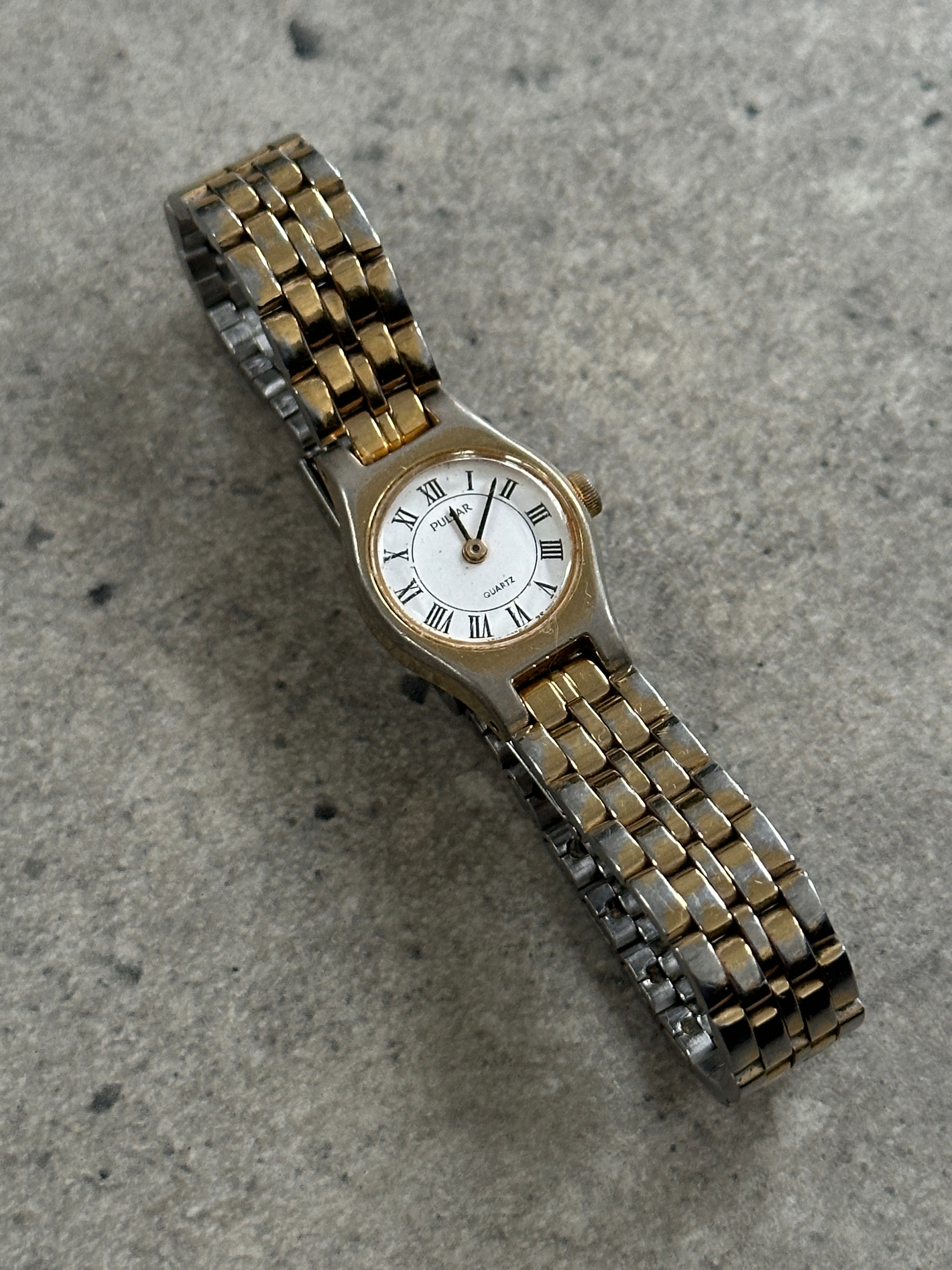 Pulsar 1990s two-tone round quartz watch with gold and silver-tone case and black leather strap.