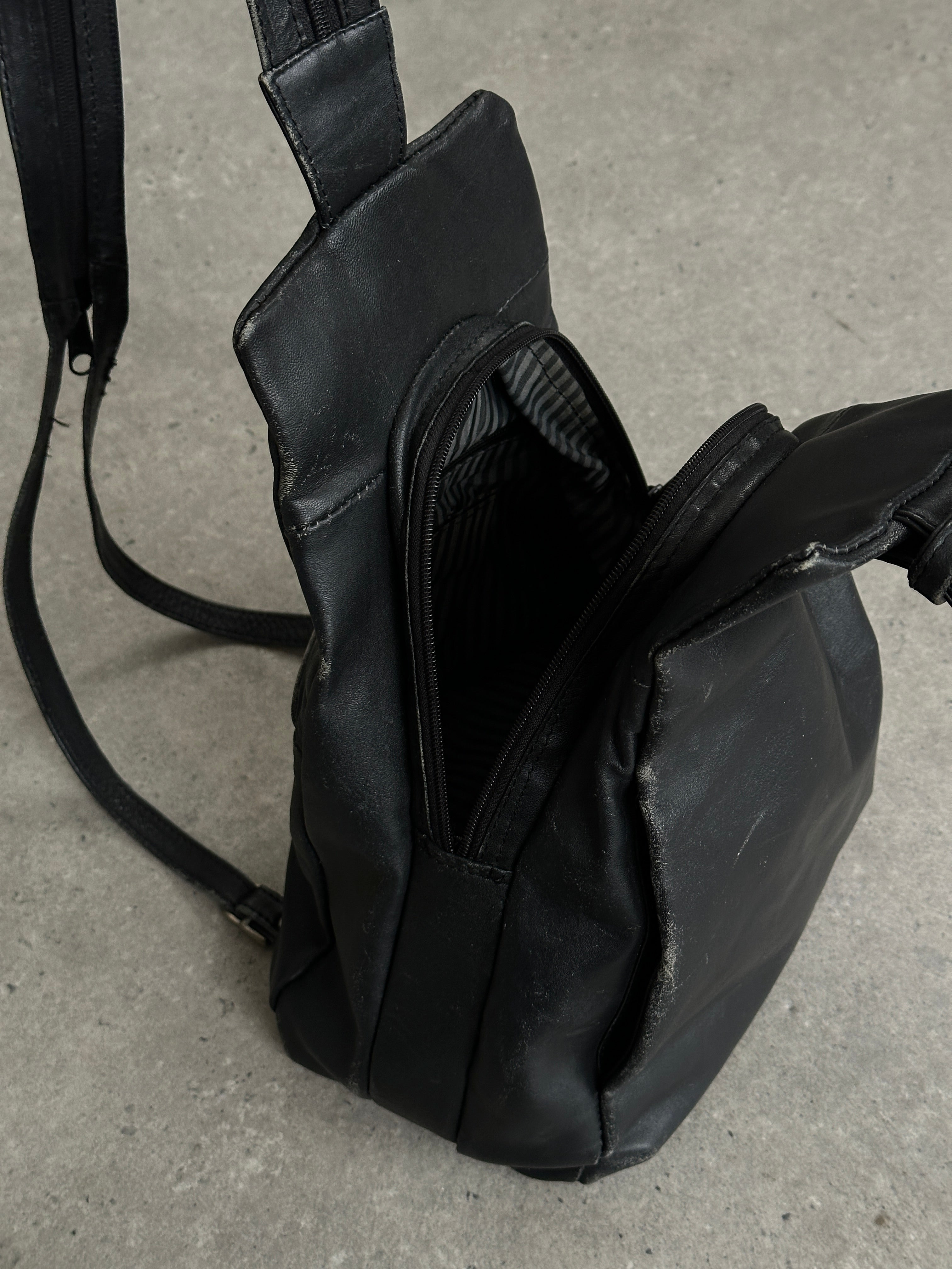Vintage distressed faux leather rucksack crossbody bag with adjustable strap and vintage-style hardware.