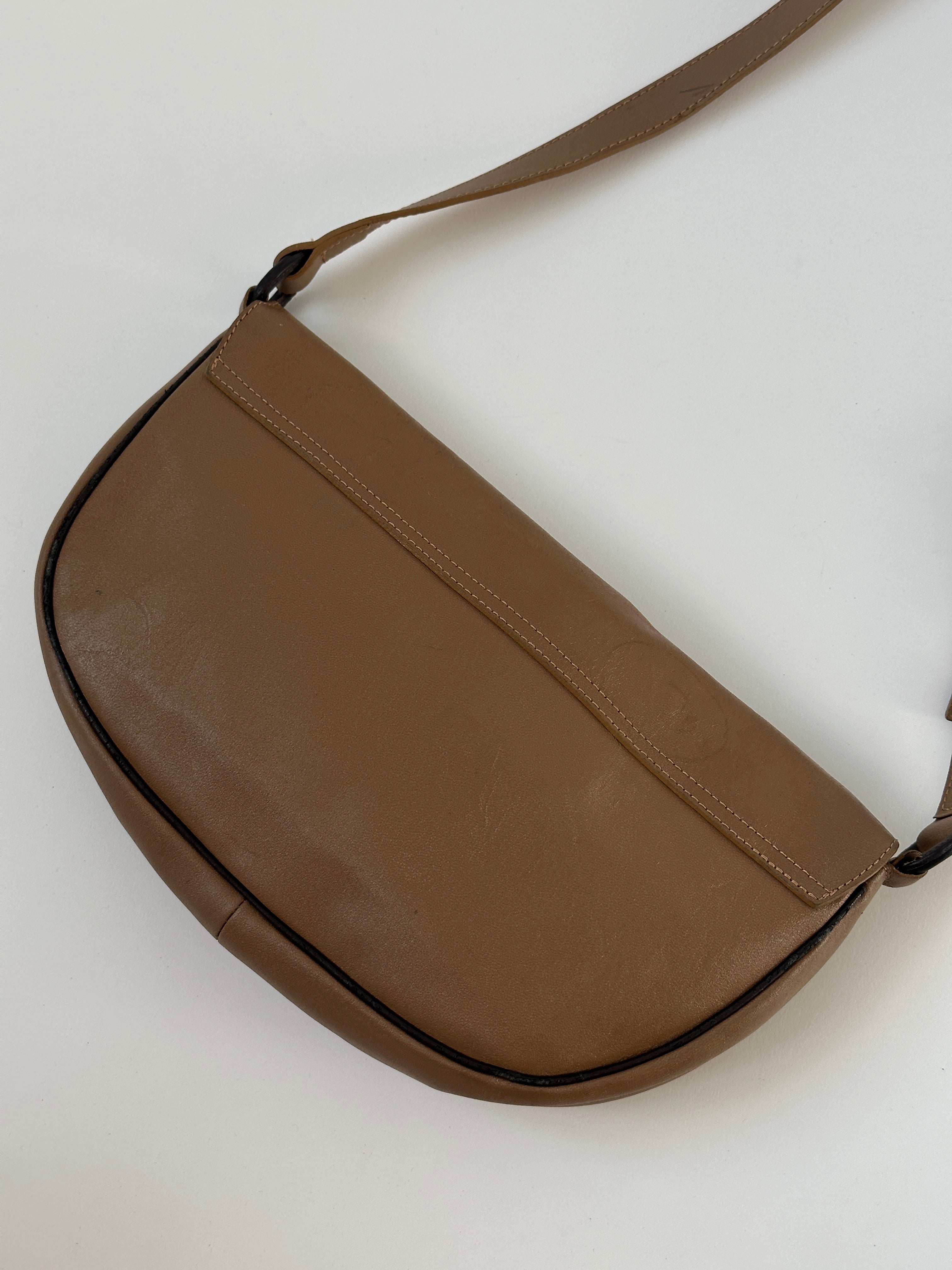 Vintage Italian leather crescent crossbody bag with aged finish, featuring a compact design and adjustable strap.
