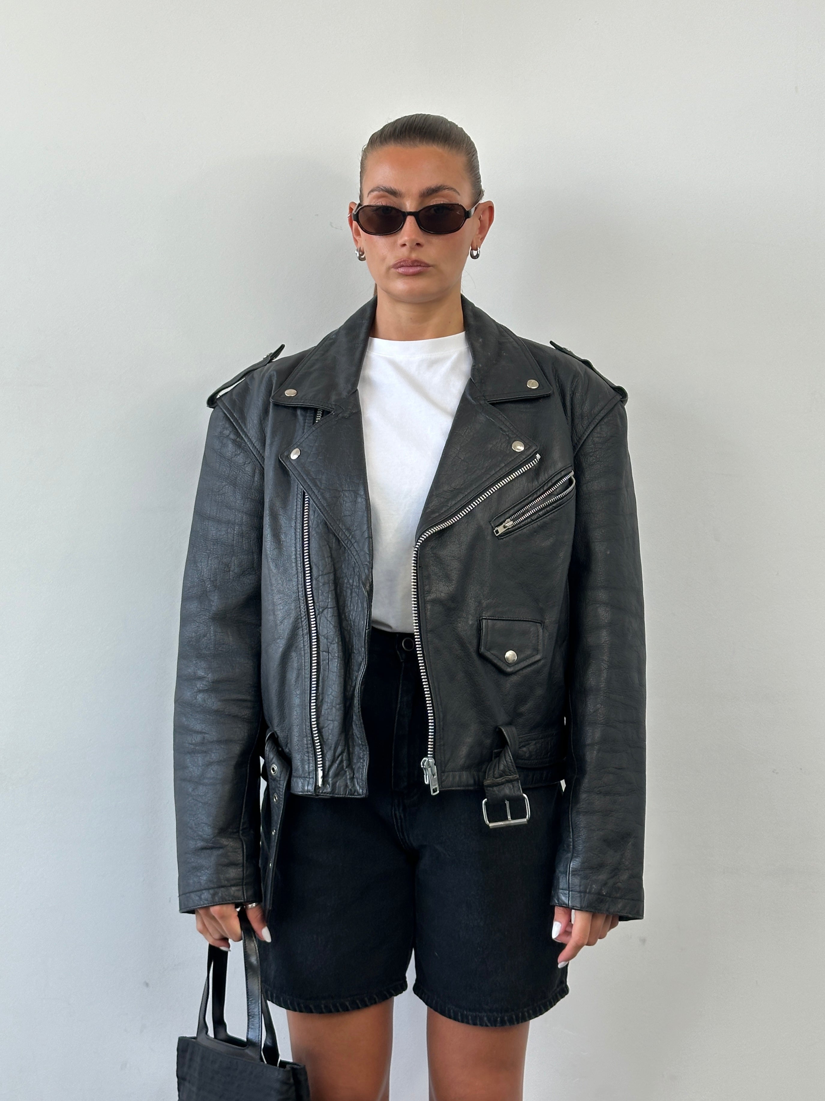 Vintage 1990s leather biker jacket in size large featuring classic design, worn leather, and metal hardware.