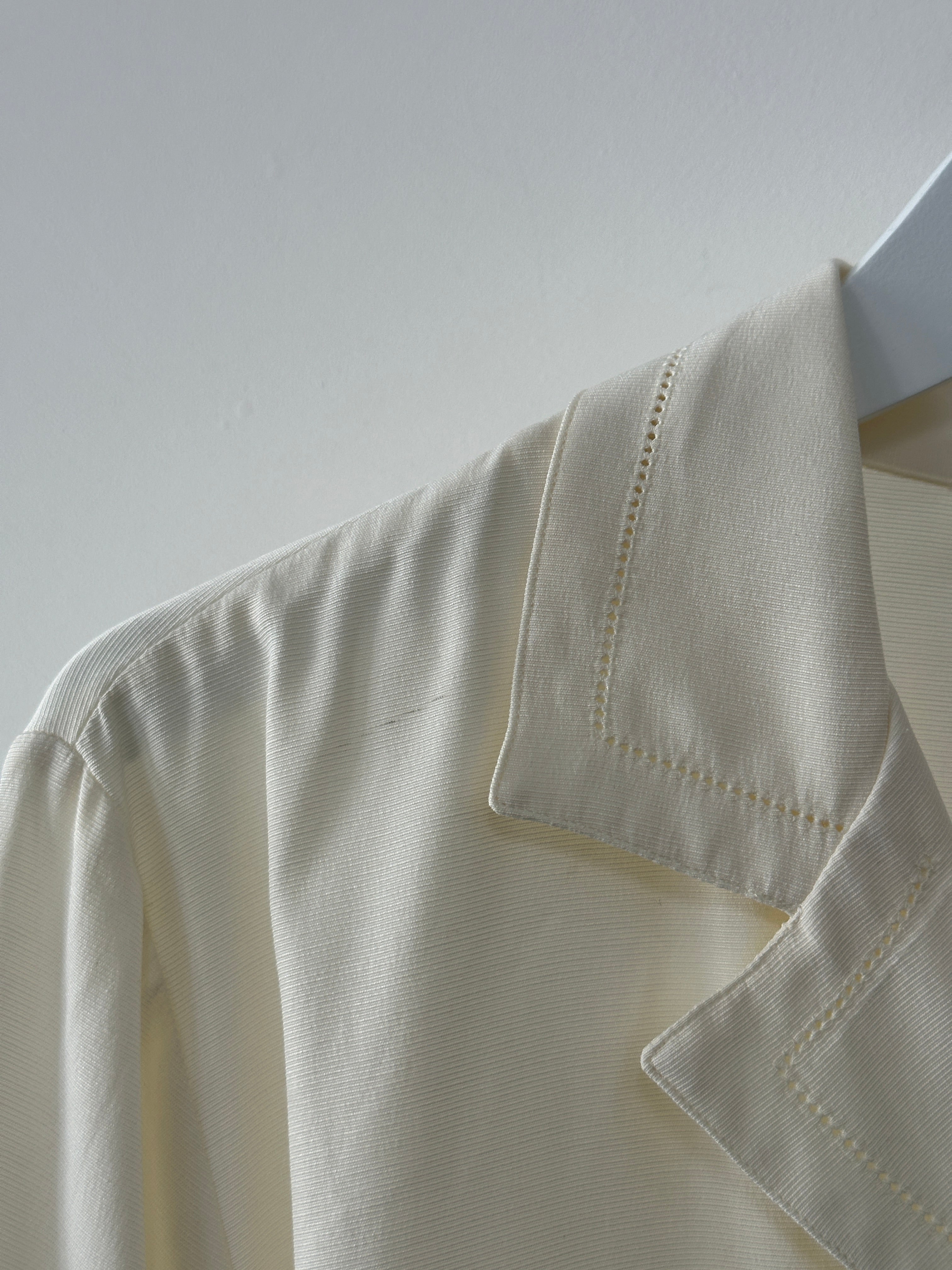 Vintage Italian vintage fitted blouse with open collar, short sleeves, and button front, displayed on a hanger.
