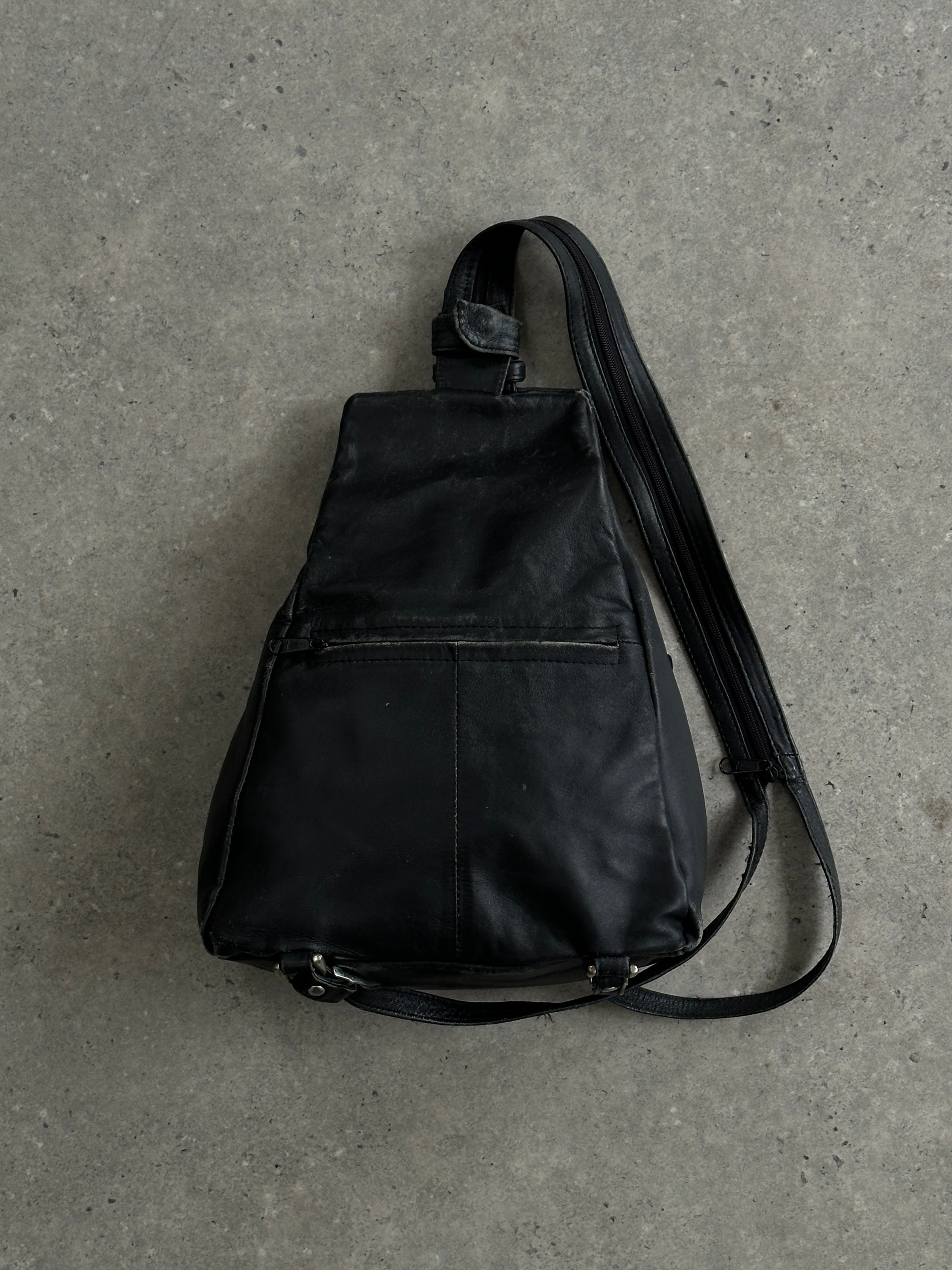 Vintage distressed faux leather rucksack crossbody bag with adjustable strap and vintage hardware details.