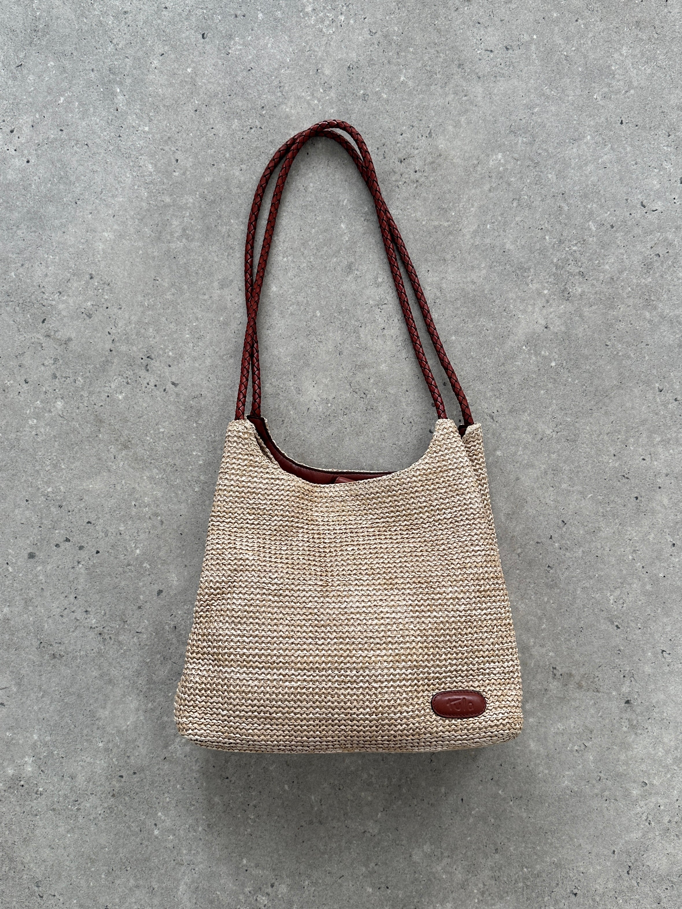 Vintage leather and straw shoulder bag with adjustable strap, showcasing a stylish blend of classic materials and craftsmanship.