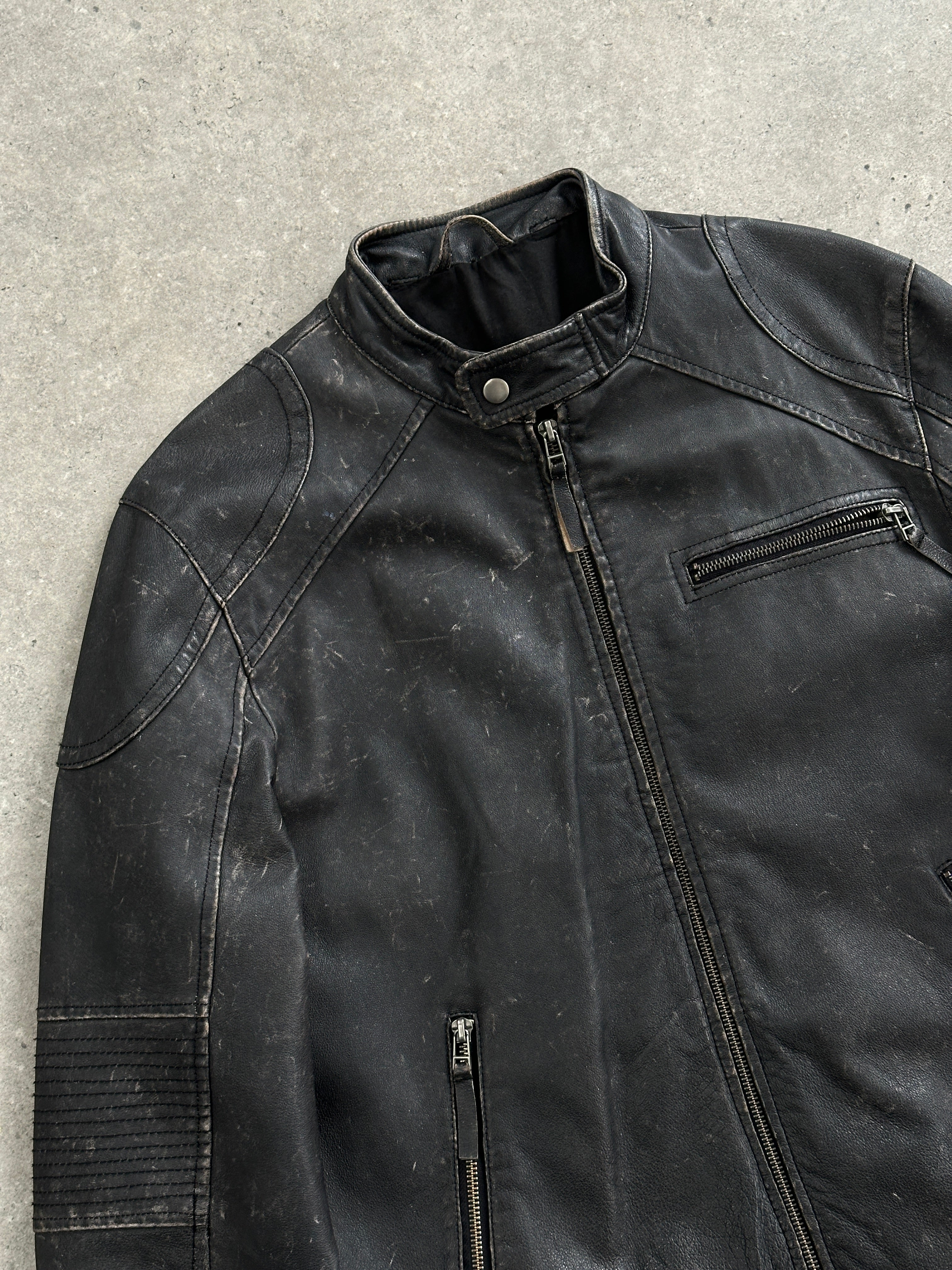 Vintage distressed leather moto jacket in size M/L, featuring a rugged design with zippered details and classic motorcycle style.
