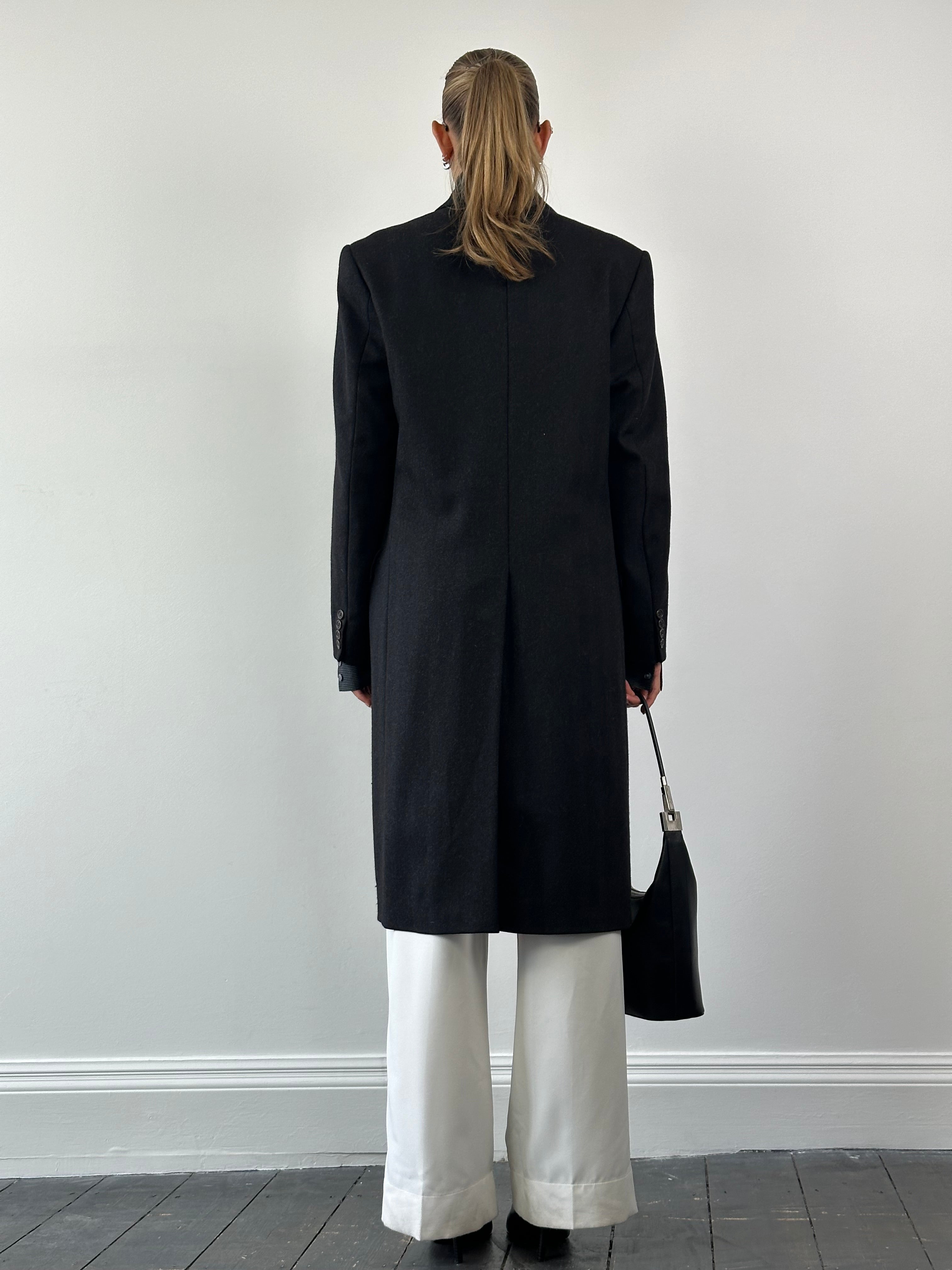 Christian Dior pure wool double-breasted coat in size L/XL displayed on a hanger, showcasing classic tailored design and sleek silhouette.