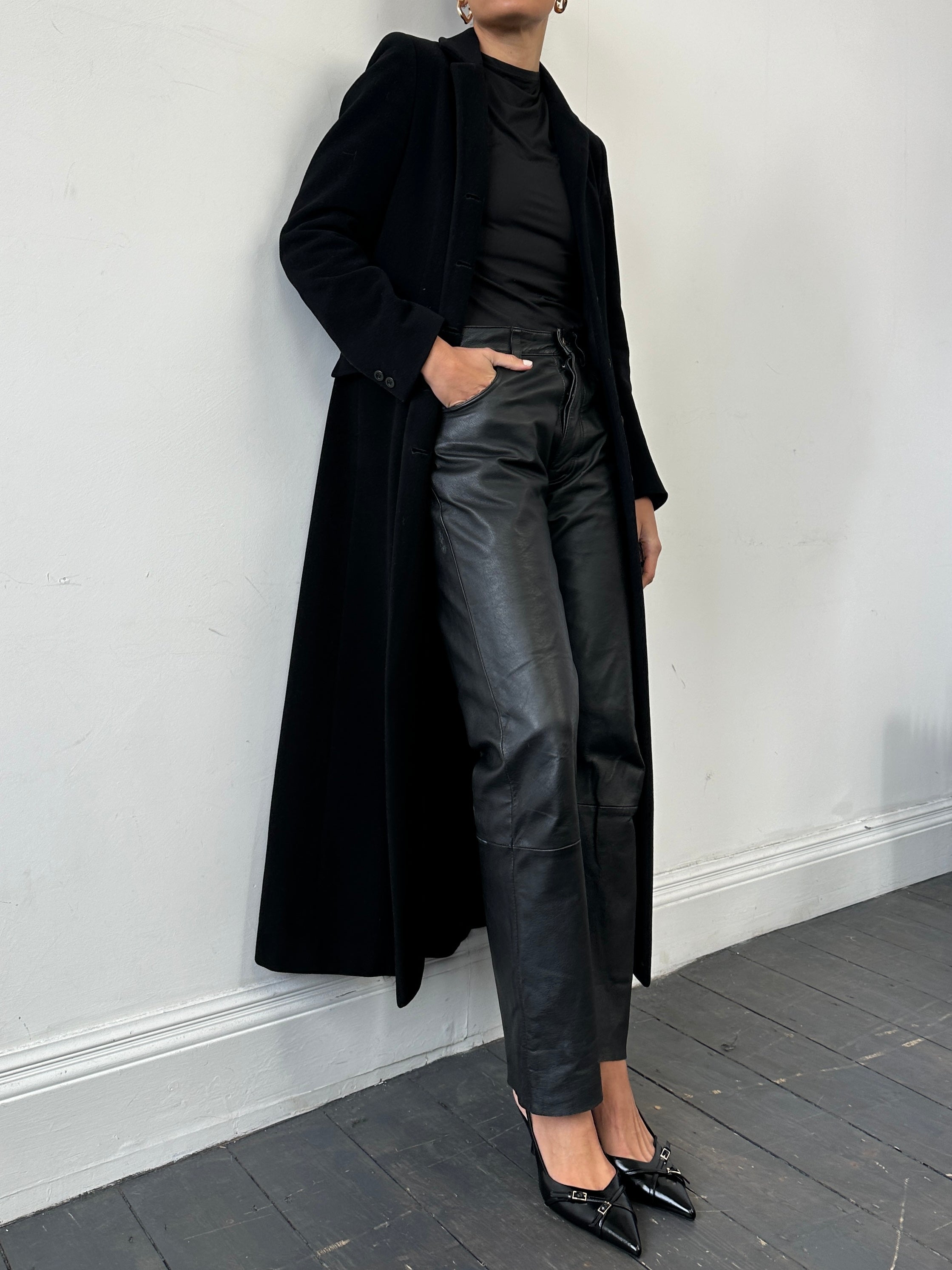 Vintage straight leg leather trousers in size W30 displayed on a hanger with visible stitching and classic design details.