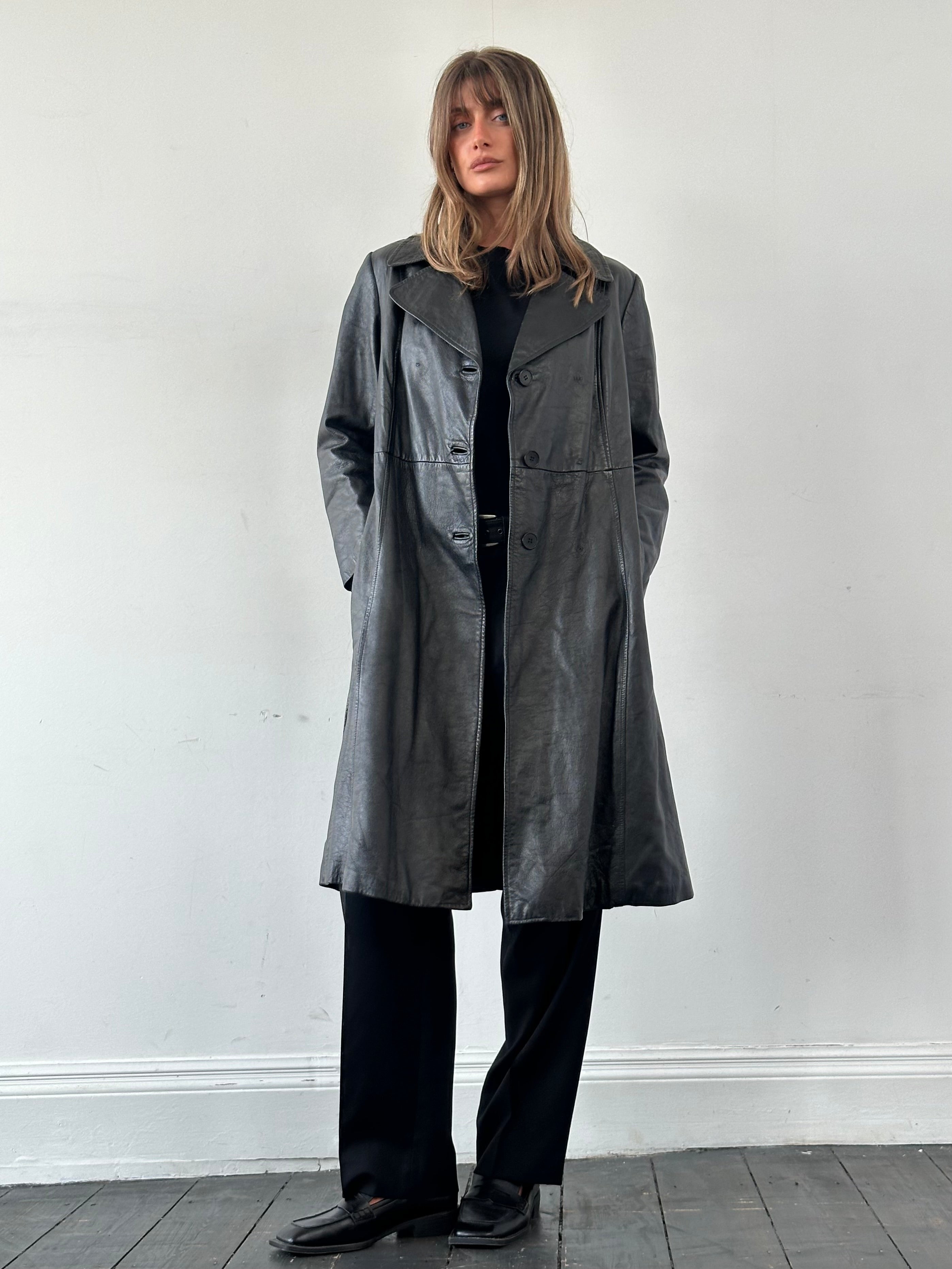Vintage leather trench coat with belt, classic design, long sleeves, and tailored fit in a vintage style on a model.