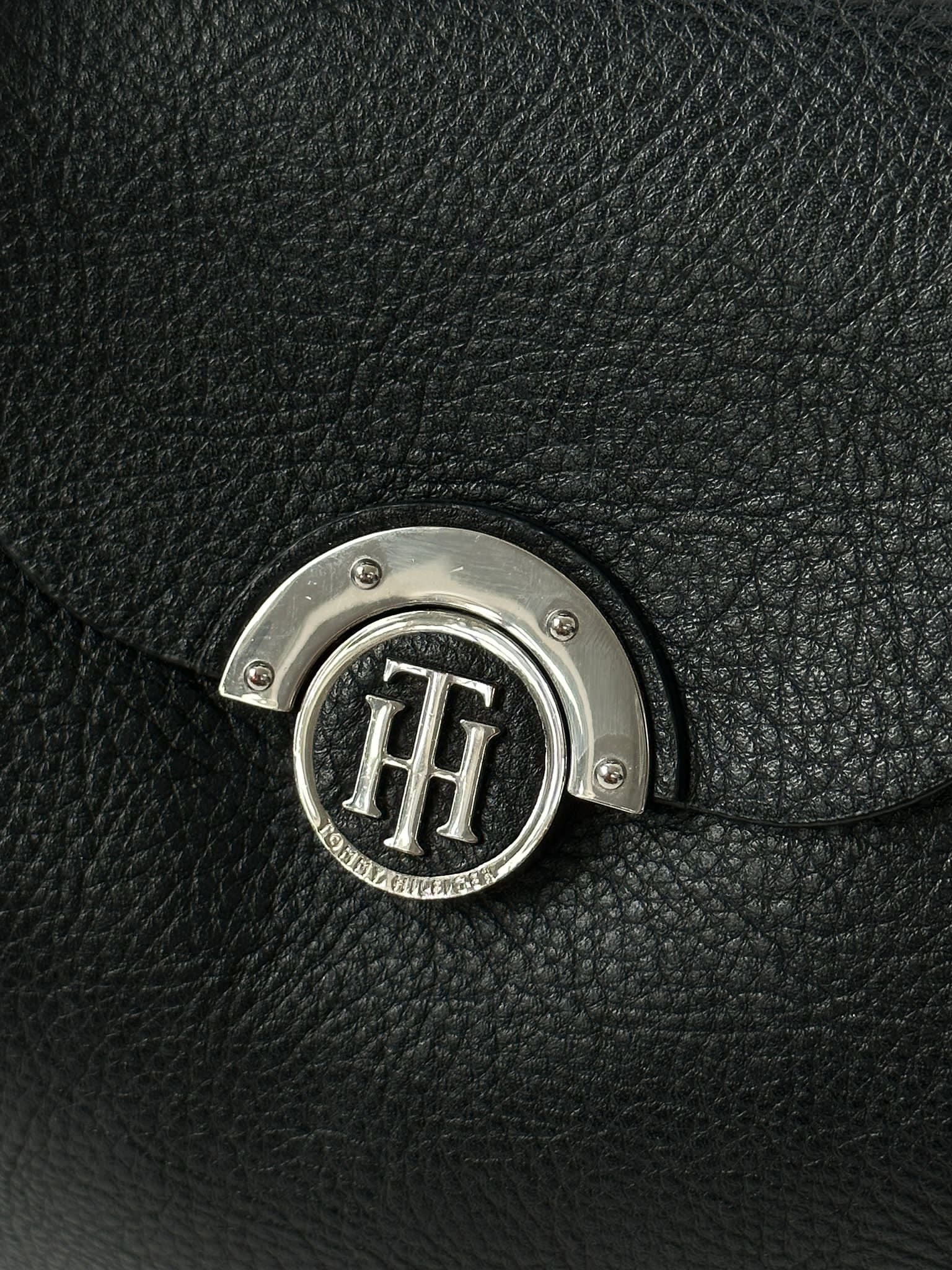 Tommy Hilfiger crossbody bag with adjustable strap, featuring signature logo and classic design, shown in a neutral color.