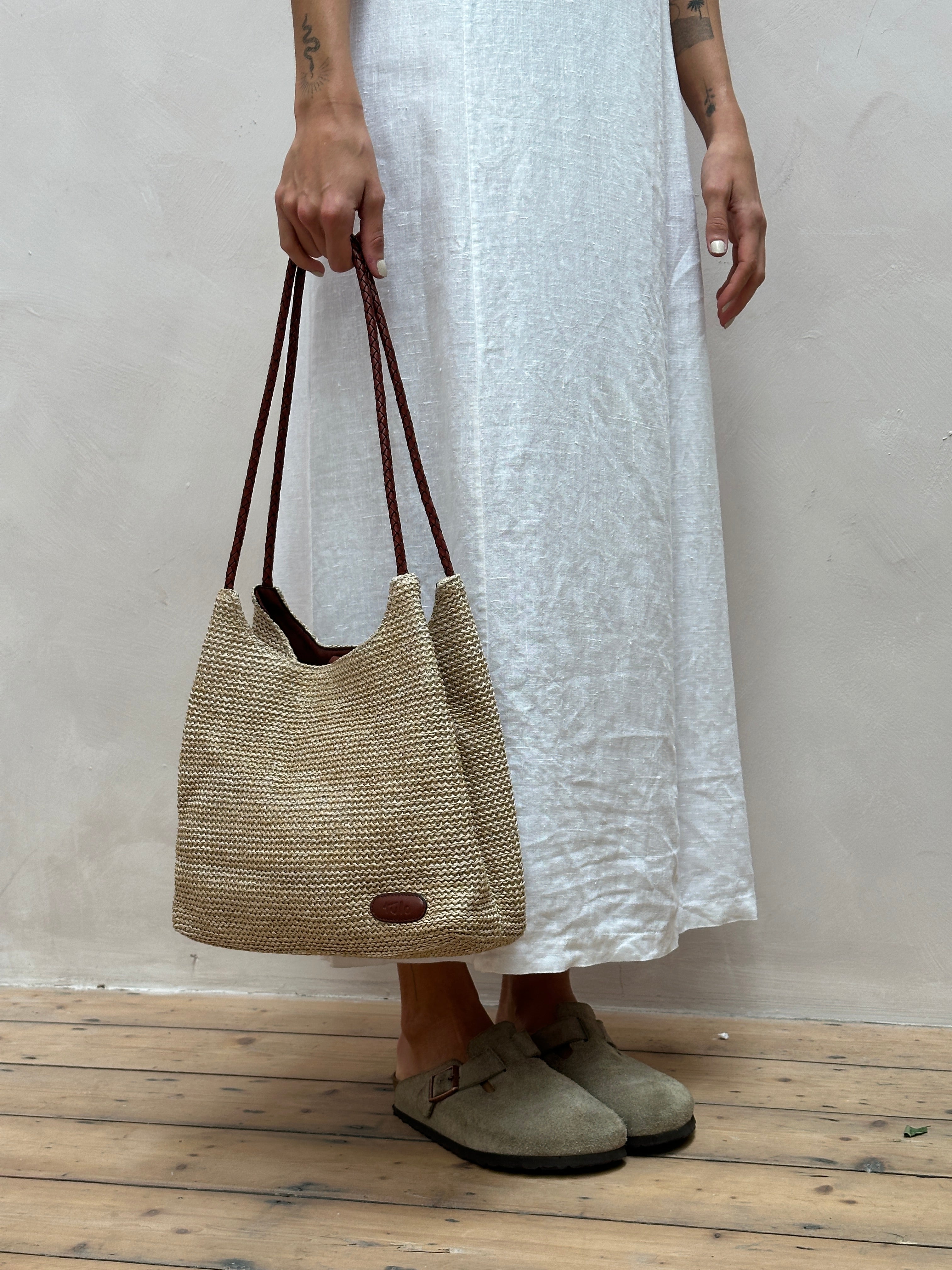 Vintage leather and straw shoulder bag with adjustable strap and rustic design, perfect for casual or boho style.