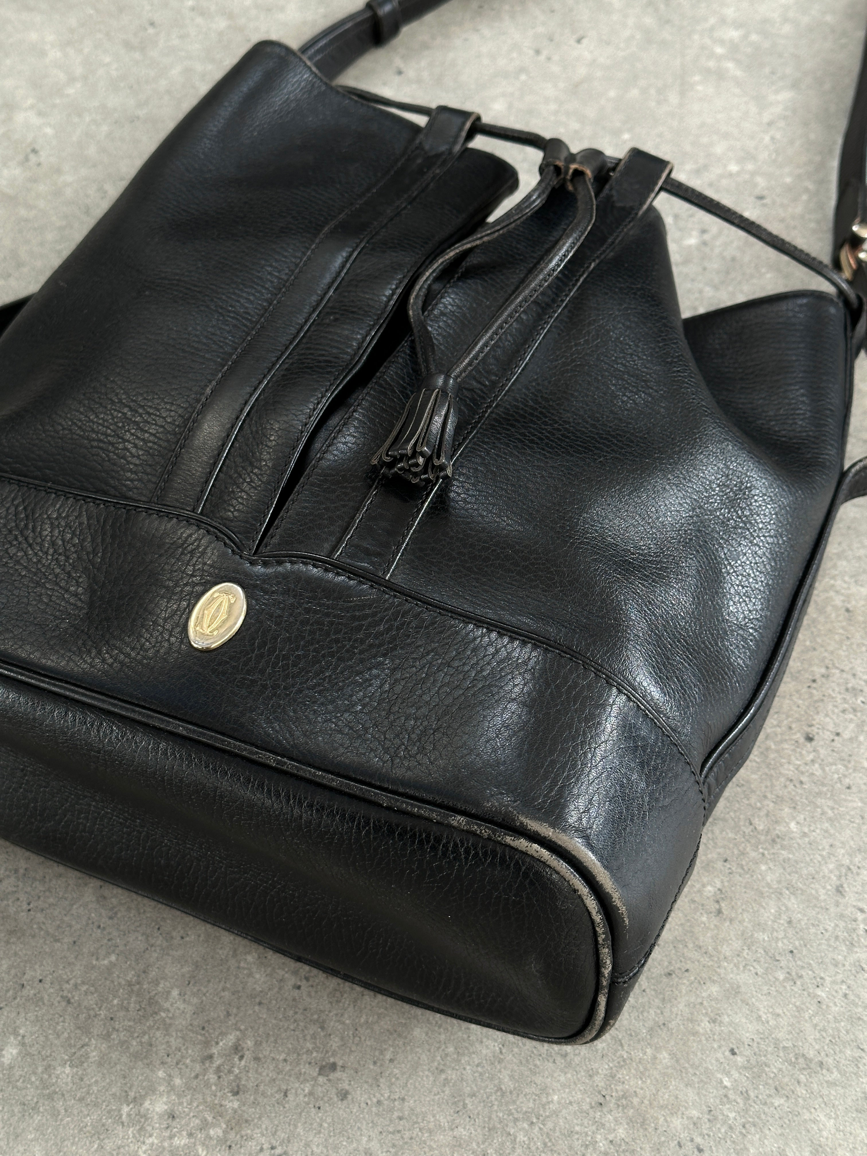 Cartier 1980s leather bucket bag with gold-tone hardware, featuring a rounded shape and adjustable strap.