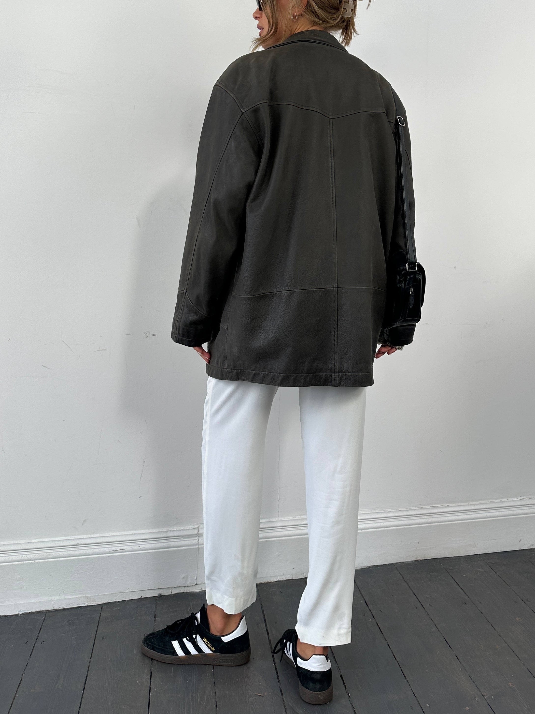 Vintage leather mid-length jacket in size L/XL, featuring classic design and smooth brown leather, displayed on a hanger.