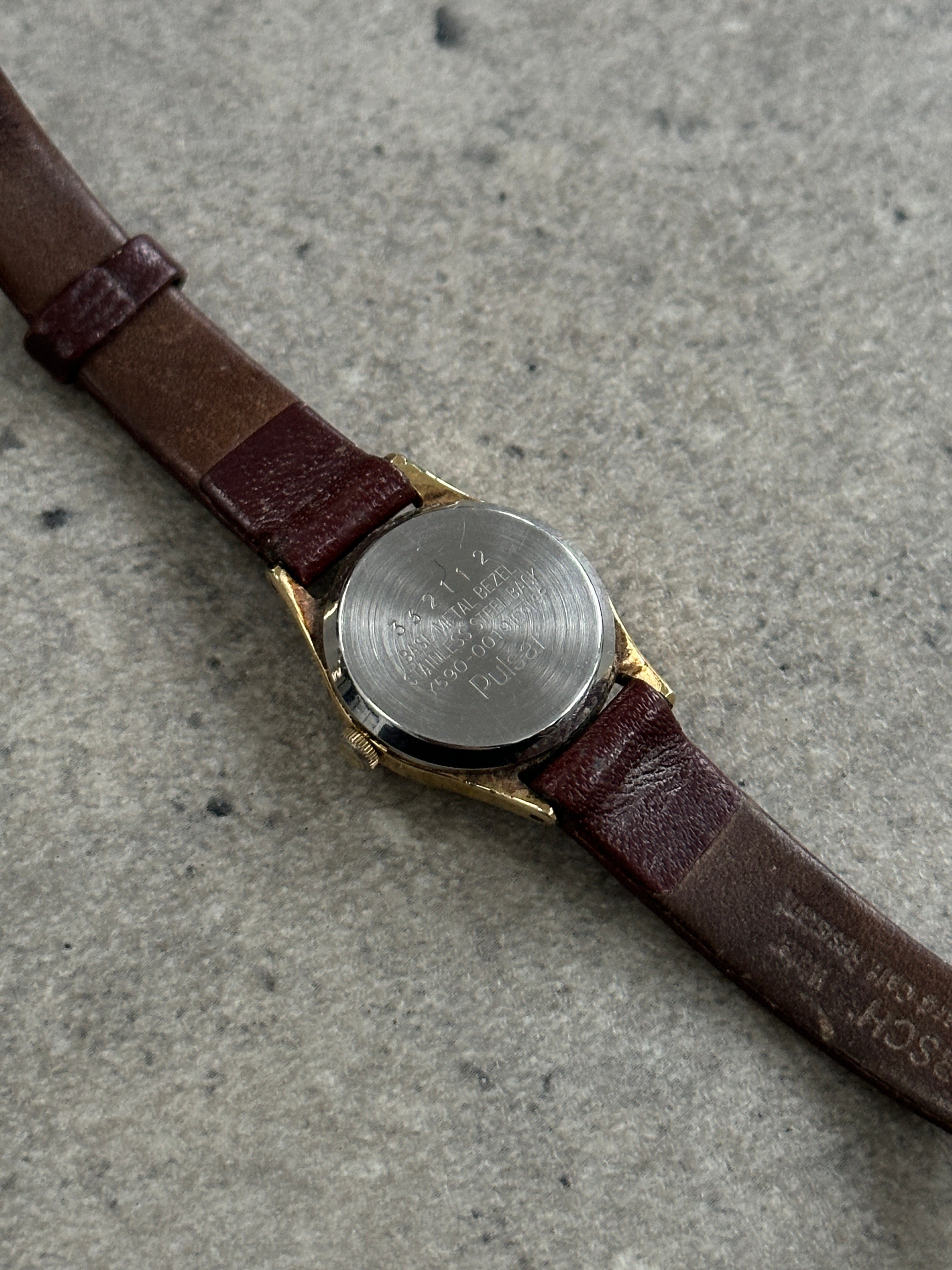Pulsar 1990s gold tone round quartz watch with classic design and metal bracelet, displayed on a neutral background.