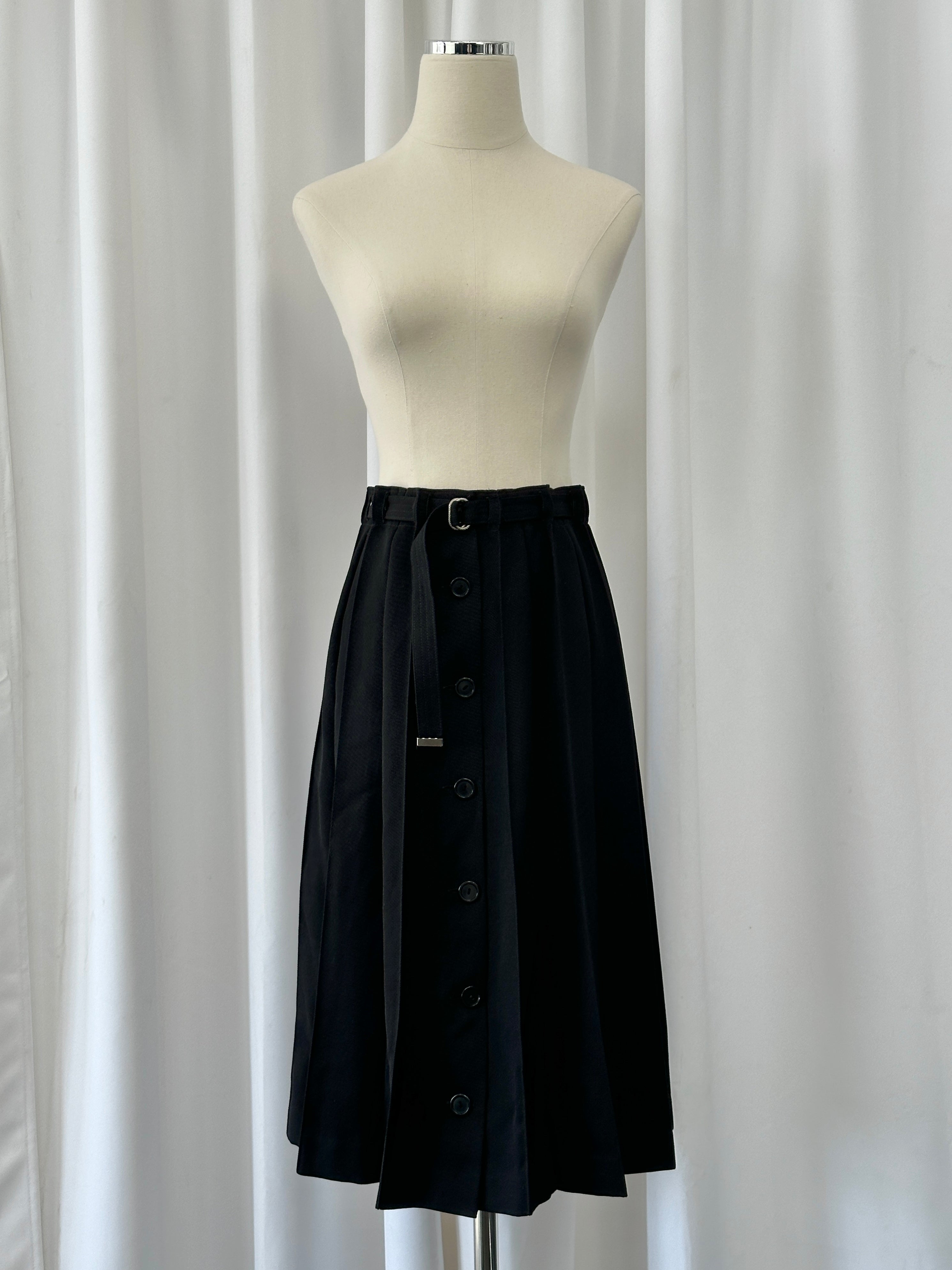 Vintage 1990s wool pleated midi skirt in deep green, featuring classic pleats and a vintage style, size W26.