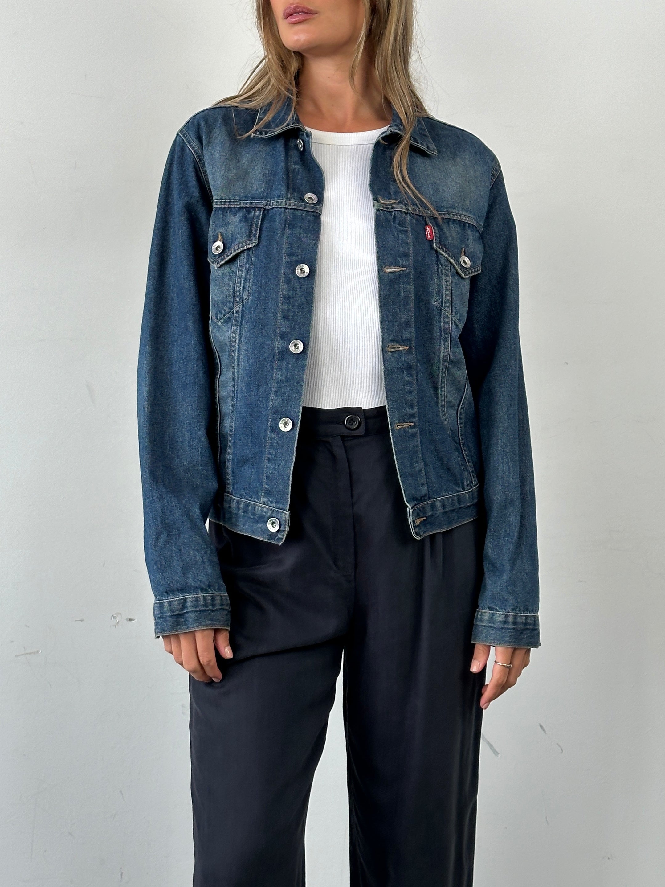 Levi’s faded denim jacket with classic design, shown in a casual fit, featuring distressed details and metal button accents.