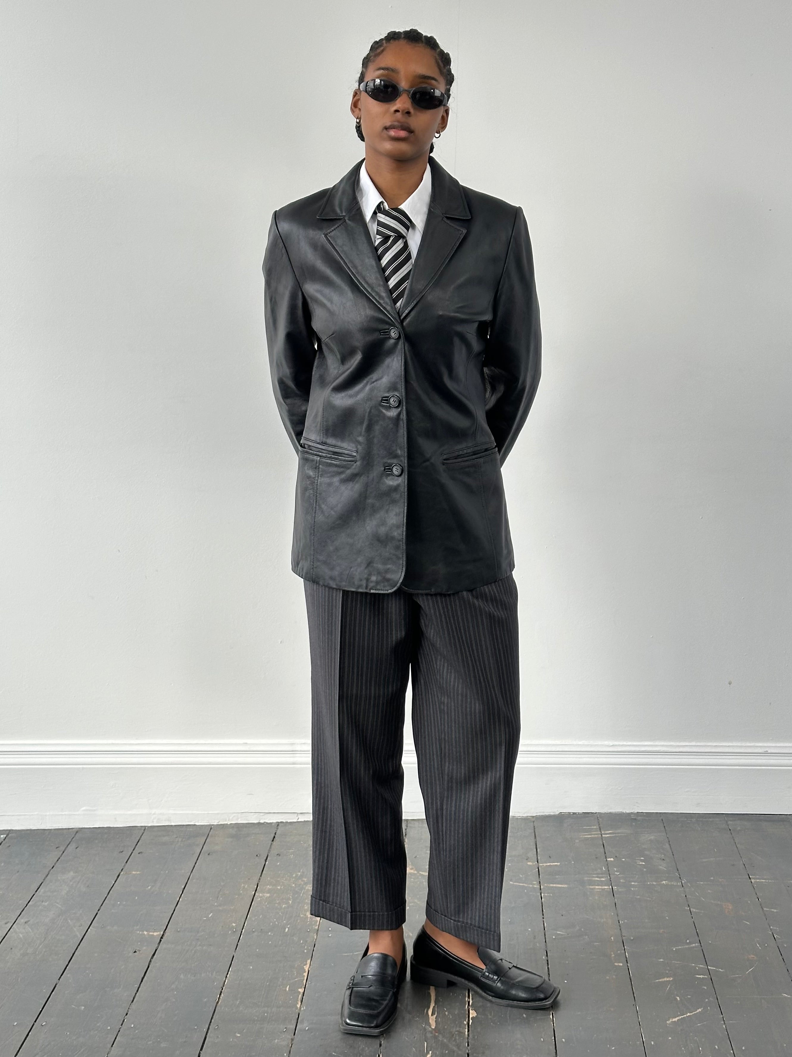 Vintage 1990s minimal leather jacket, size M, featuring sleek design and classic black leather, on a plain background.