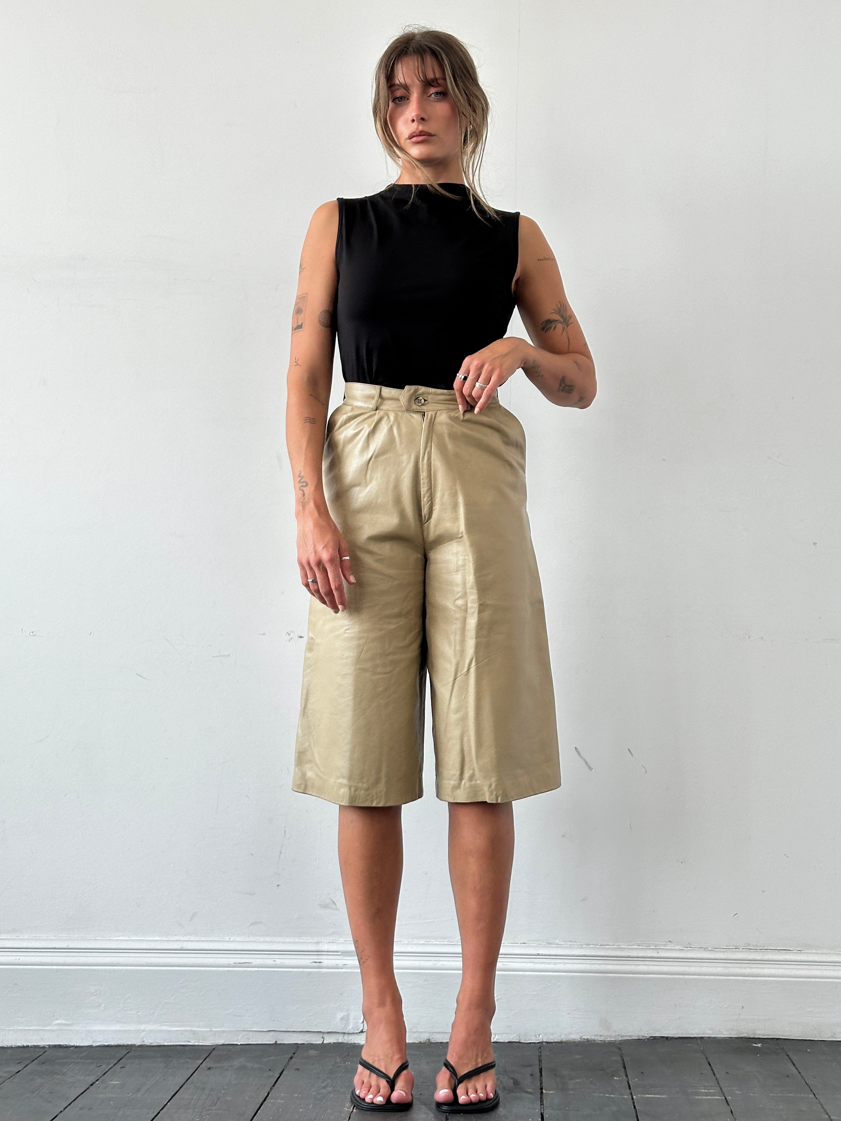 Vintage leather wide-leg high-waisted shorts, long style, shown in natural brown leather with detailed stitching and a relaxed fit.