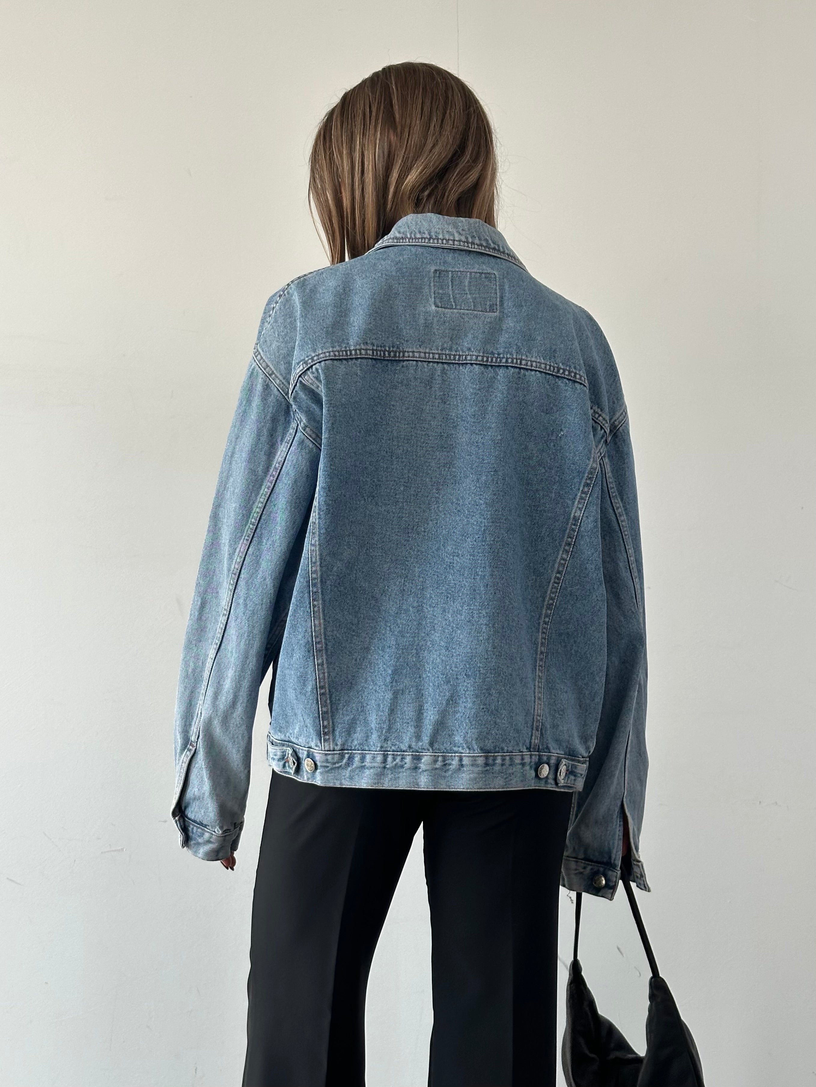Vintage oversized denim jacket in XL style, featuring classic blue denim fabric and relaxed fit, displayed on a hanger.