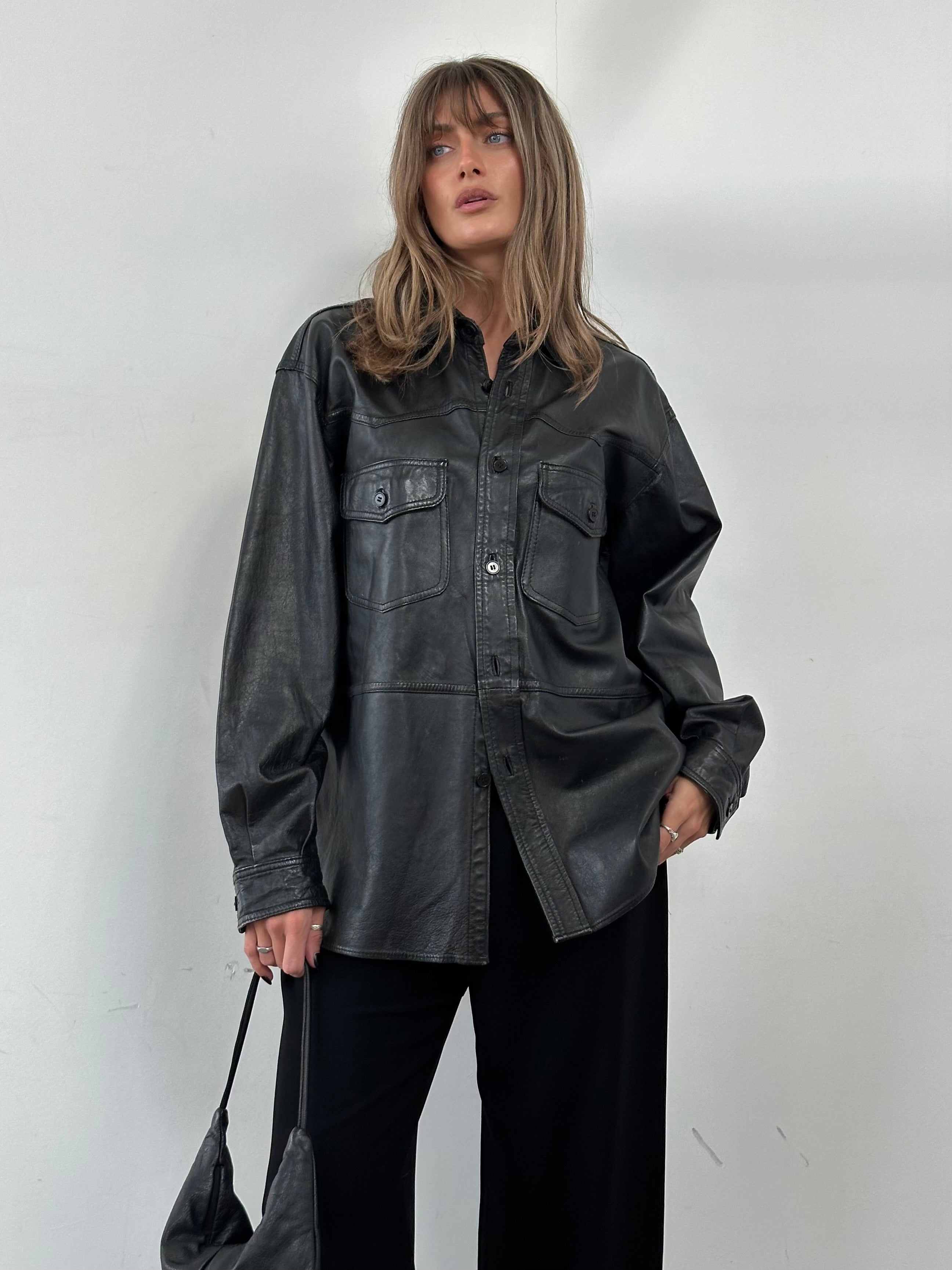 Vintage leather shirt in size L/XL displayed, featuring classic design and rich brown leather material.