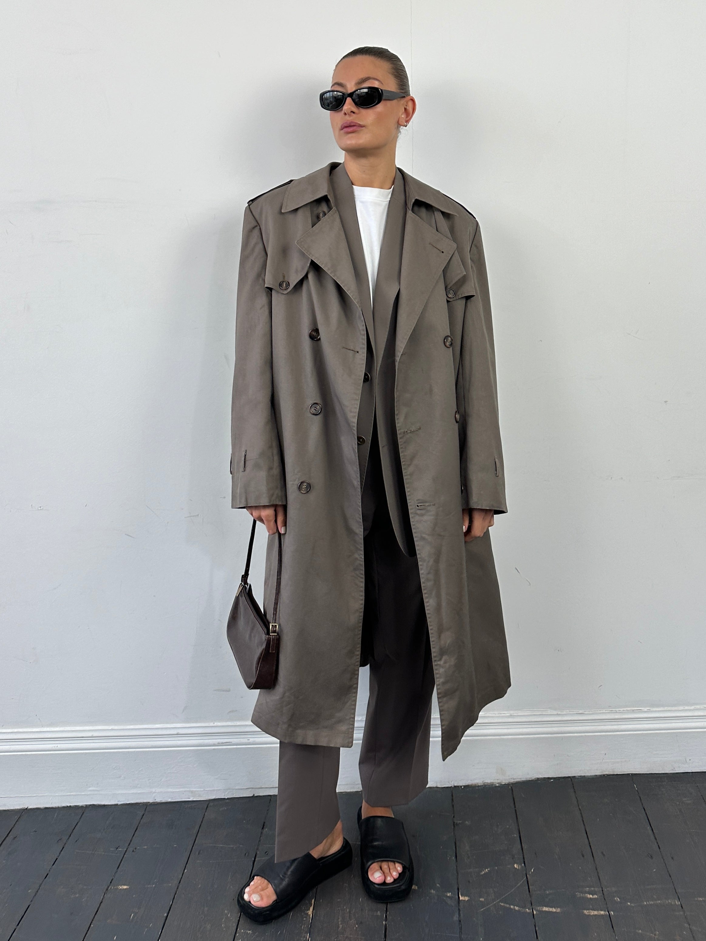Christian Dior Monsieur double-breasted belted trench coat in XL, displayed on a hanger with classic beige fabric and belt details.