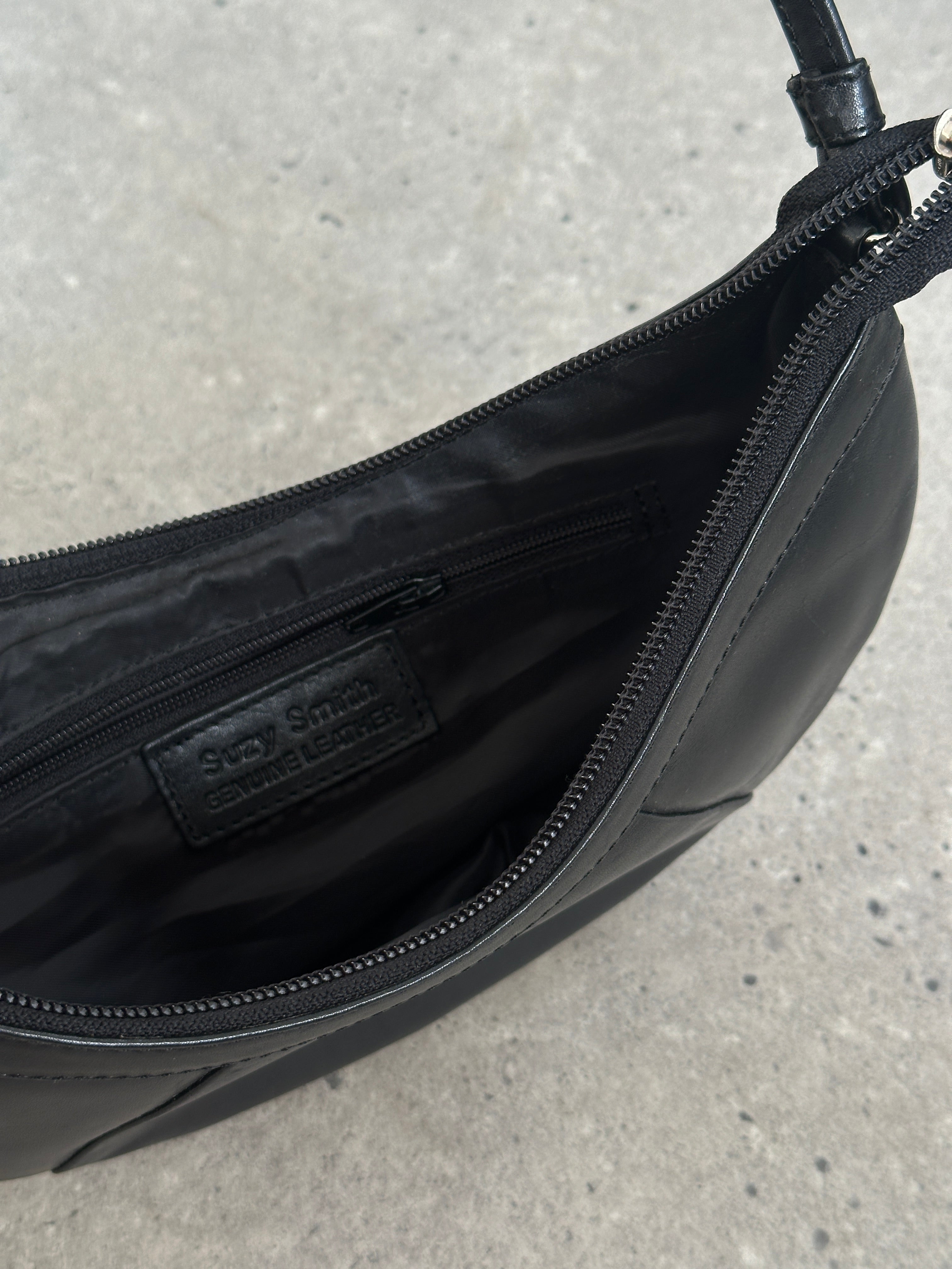 Vintage leather crescent shoulder bag with adjustable strap, featuring a classic design and aged leather finish.