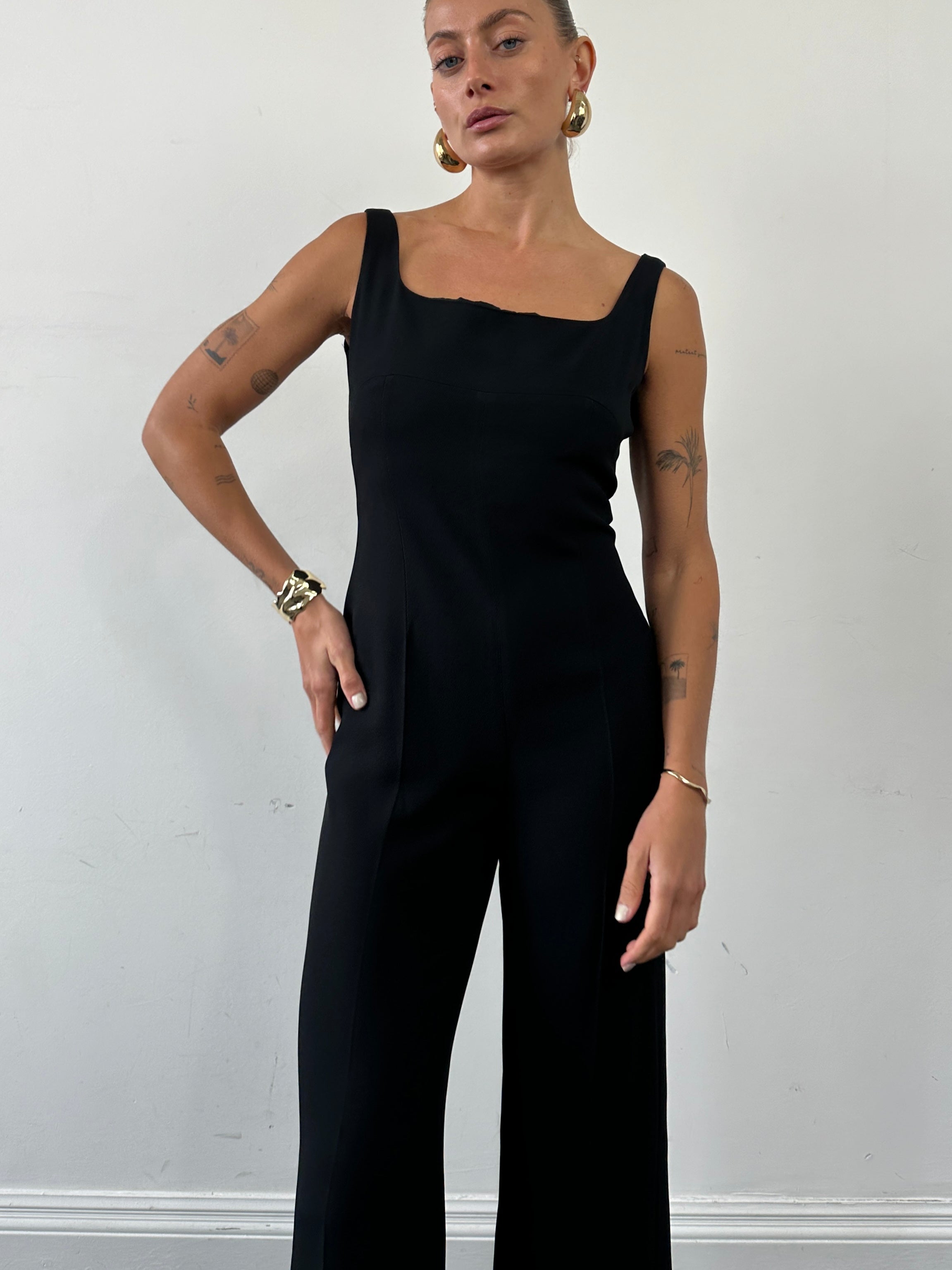 Max Mara square neck jumpsuit in black, featuring long sleeves and a fitted waist, displayed on a hanger.