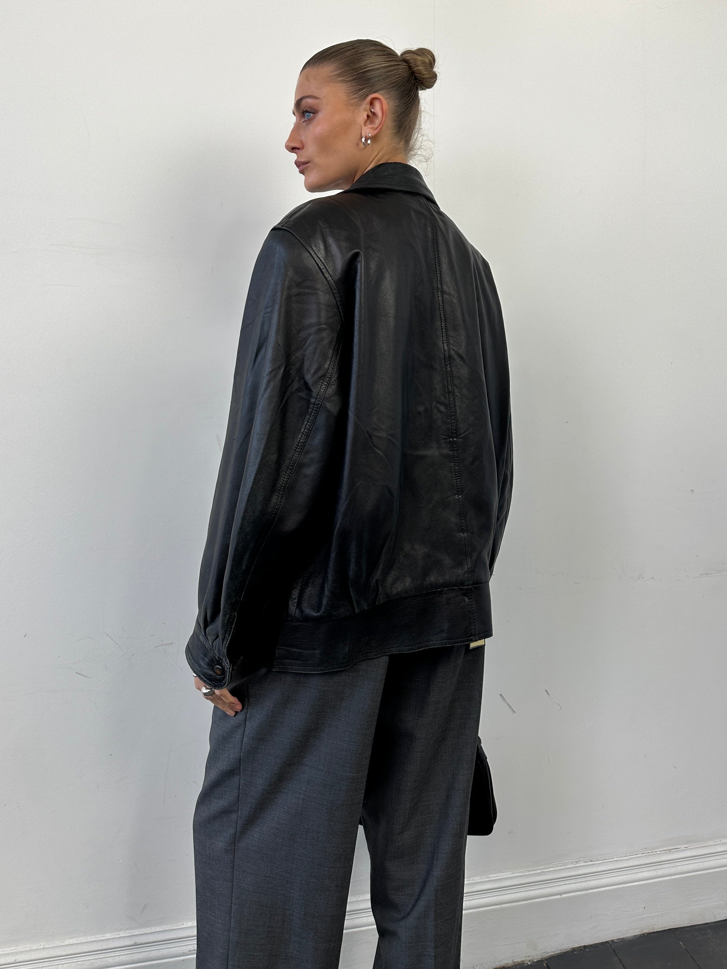 Vintage leather bomber jacket in size M/L, featuring classic design with ribbed cuffs and collar, on a neutral background.