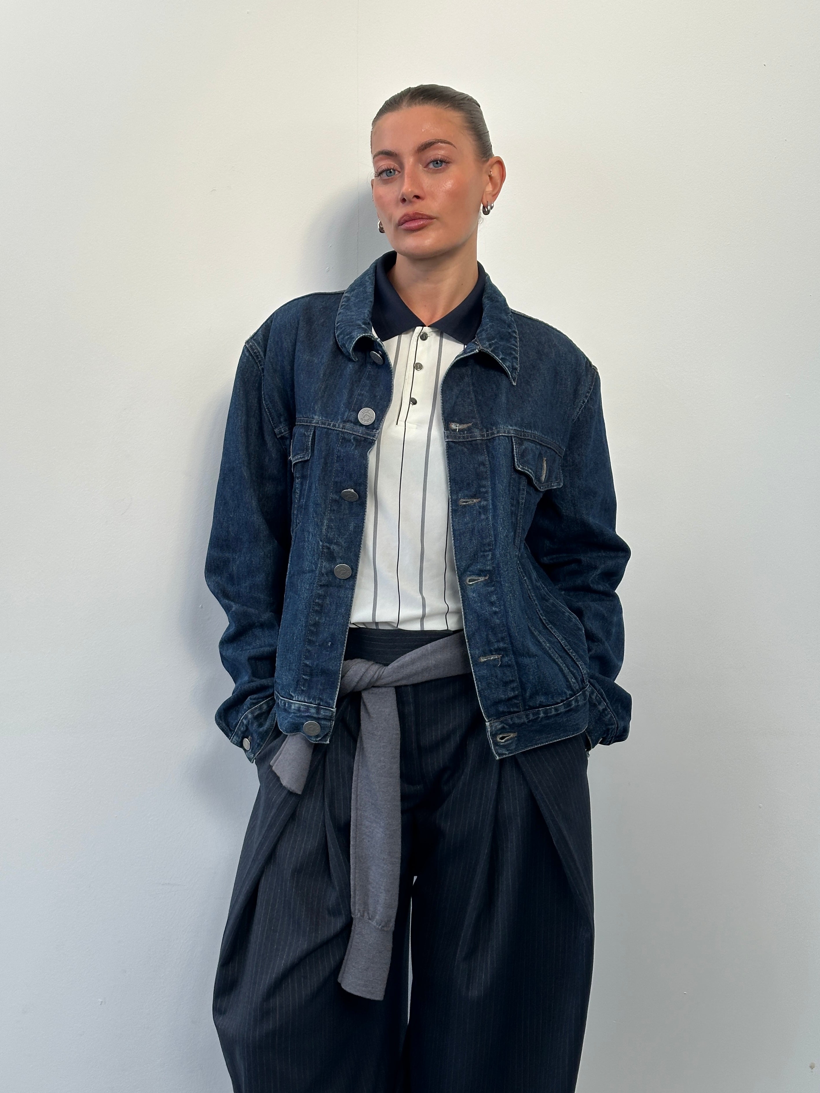 Armani Jeans 1900s mid-wash denim jacket in size L displayed on a hanger, featuring classic styling and visible stitching details.