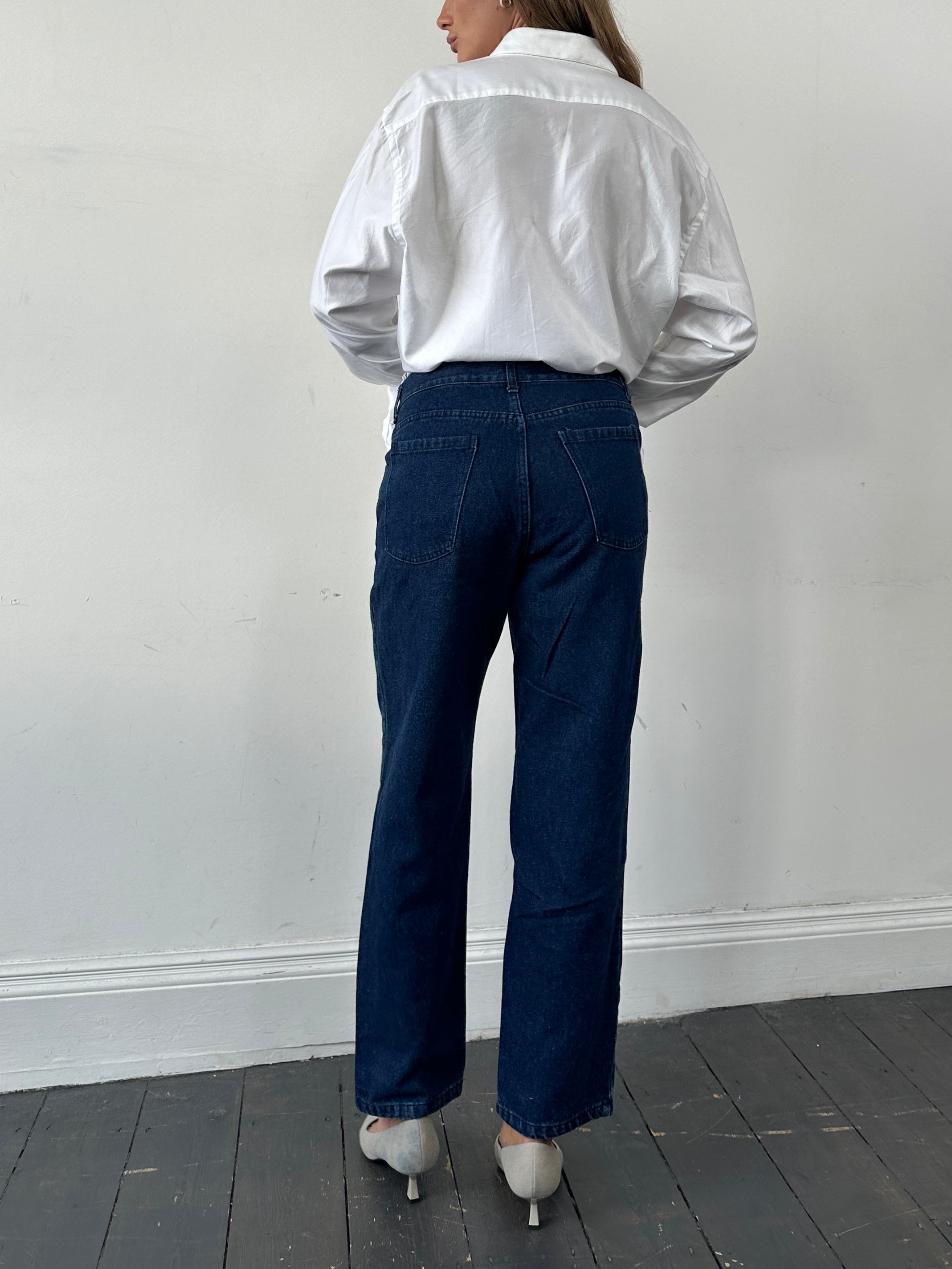 Vintage high waisted straight leg denim jeans in classic blue, shown on a hanger with visible stitching and pockets.