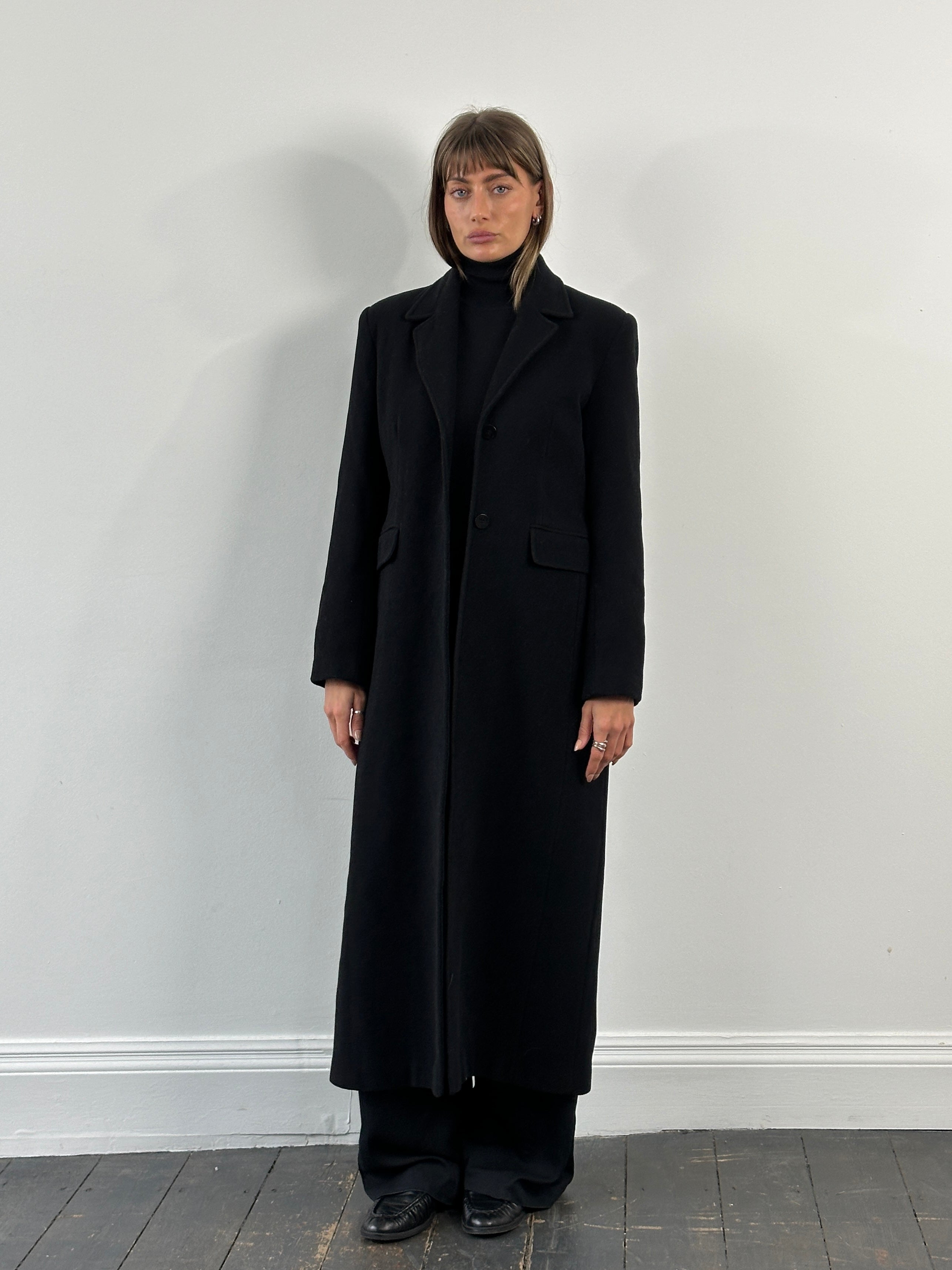 Vintage 1990s wool floor-length coat in size S/M, shown hanging on a wooden hanger with a classic collar and long sleeves.