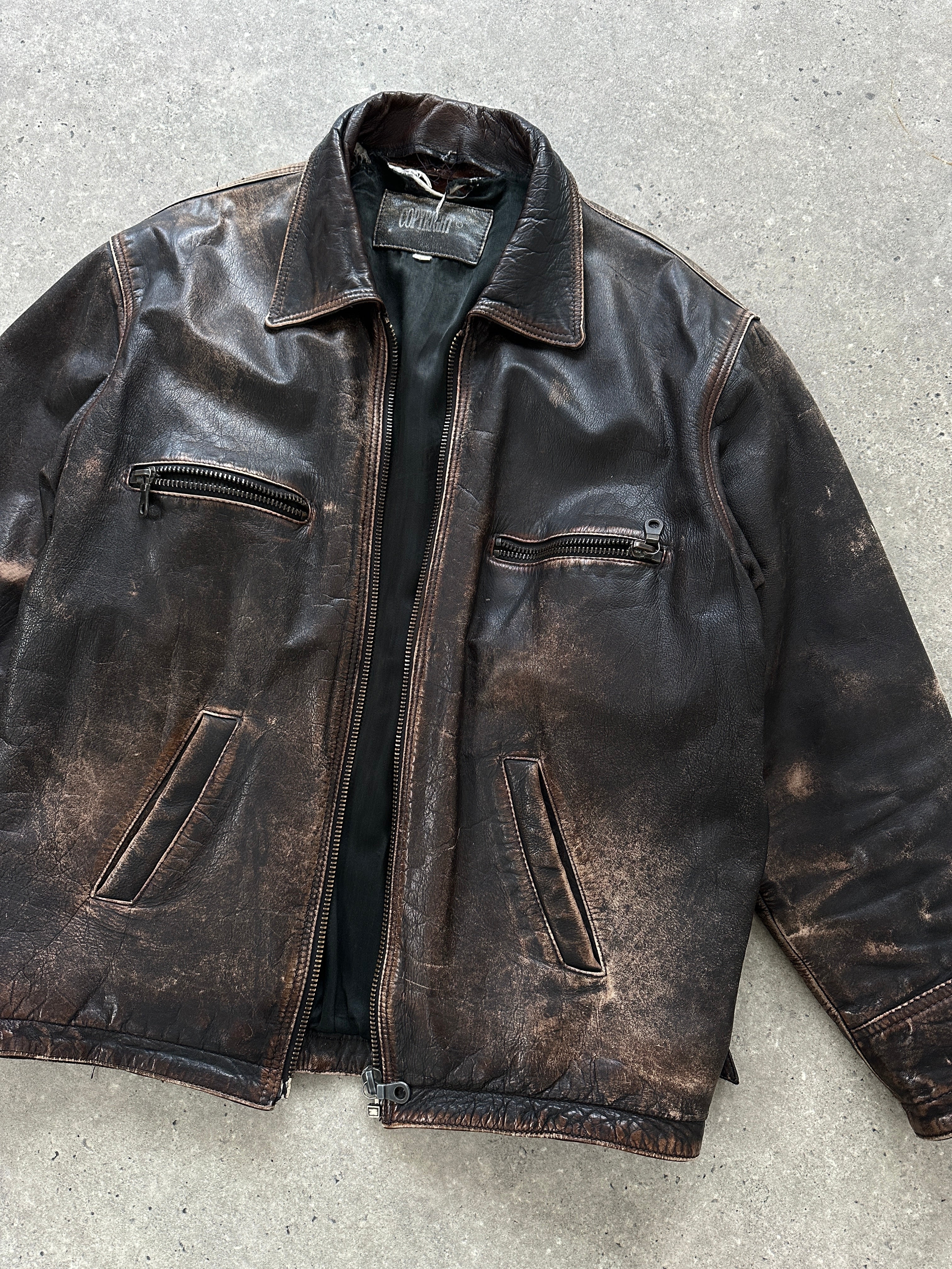 Vintage distressed leather jacket in size M/L, featuring rugged design and worn-in style, shown on a model.
