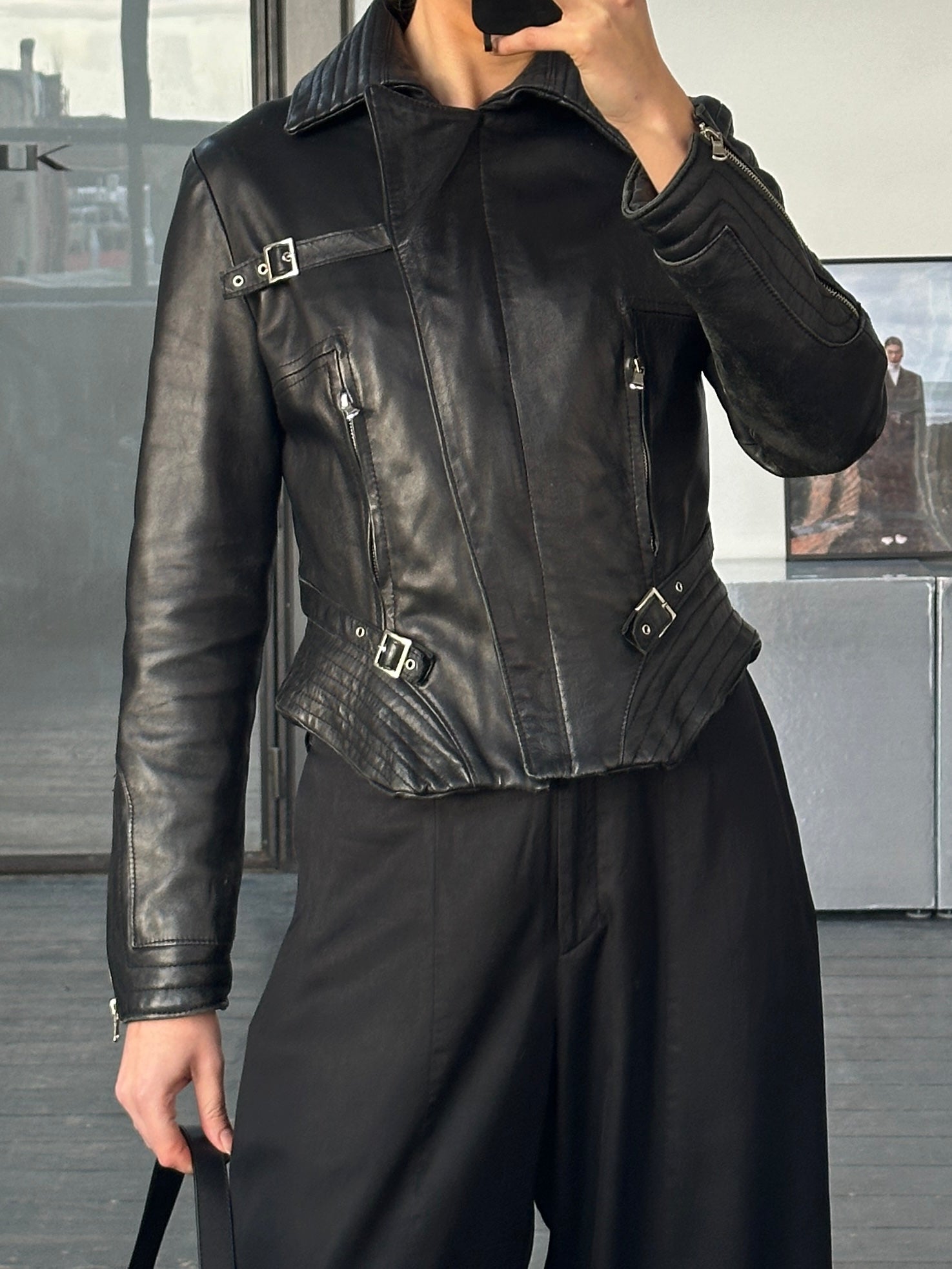 Vintage Italian 1990s fitted leather jacket with buckled details, in classic brown leather, displayed on a hanger.