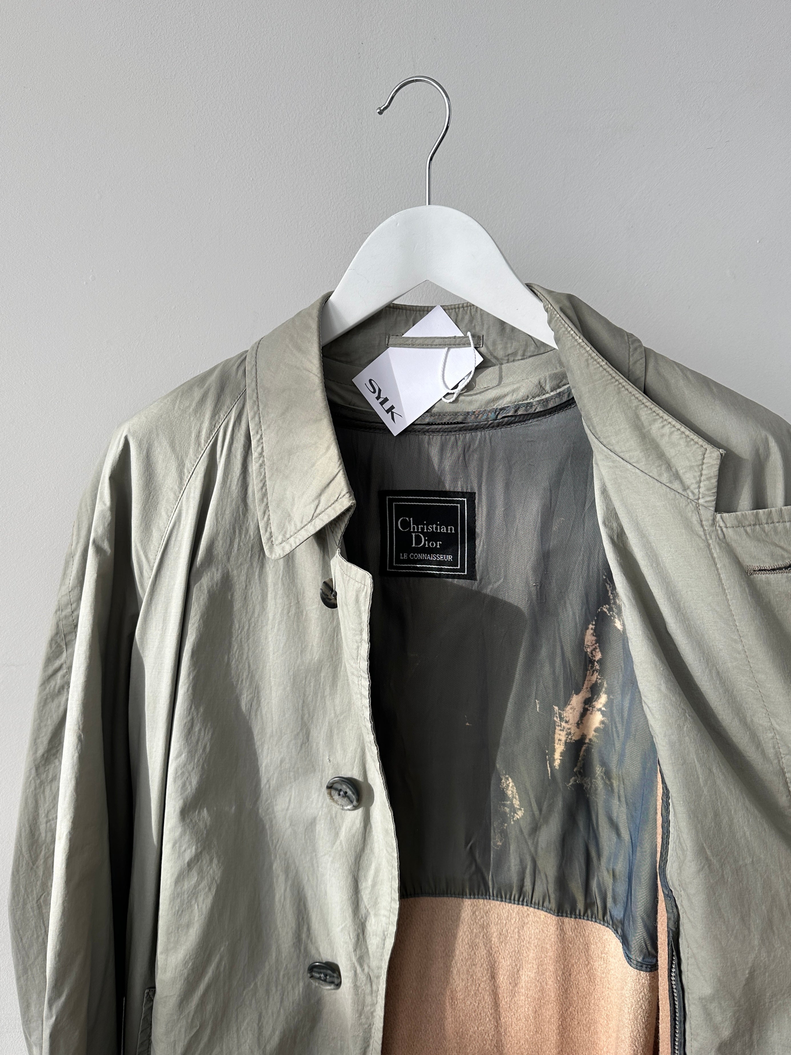 Christian Dior Le Connaisseur belted trench coat in classic beige, stylishly displayed with belt and double-breasted design.