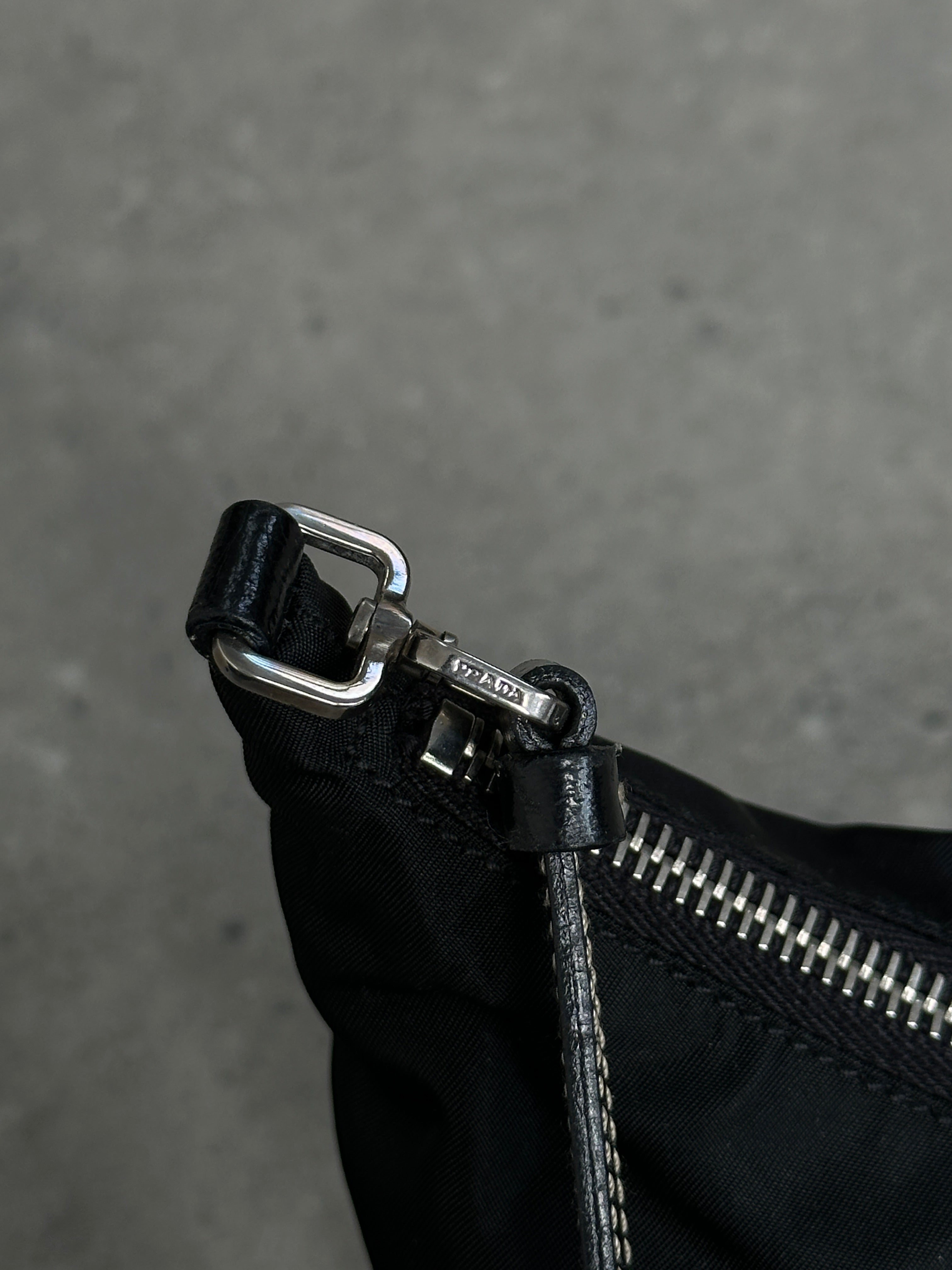 Prada nylon shoulder bag with chrome logo hardware, featuring a sleek design and adjustable strap.