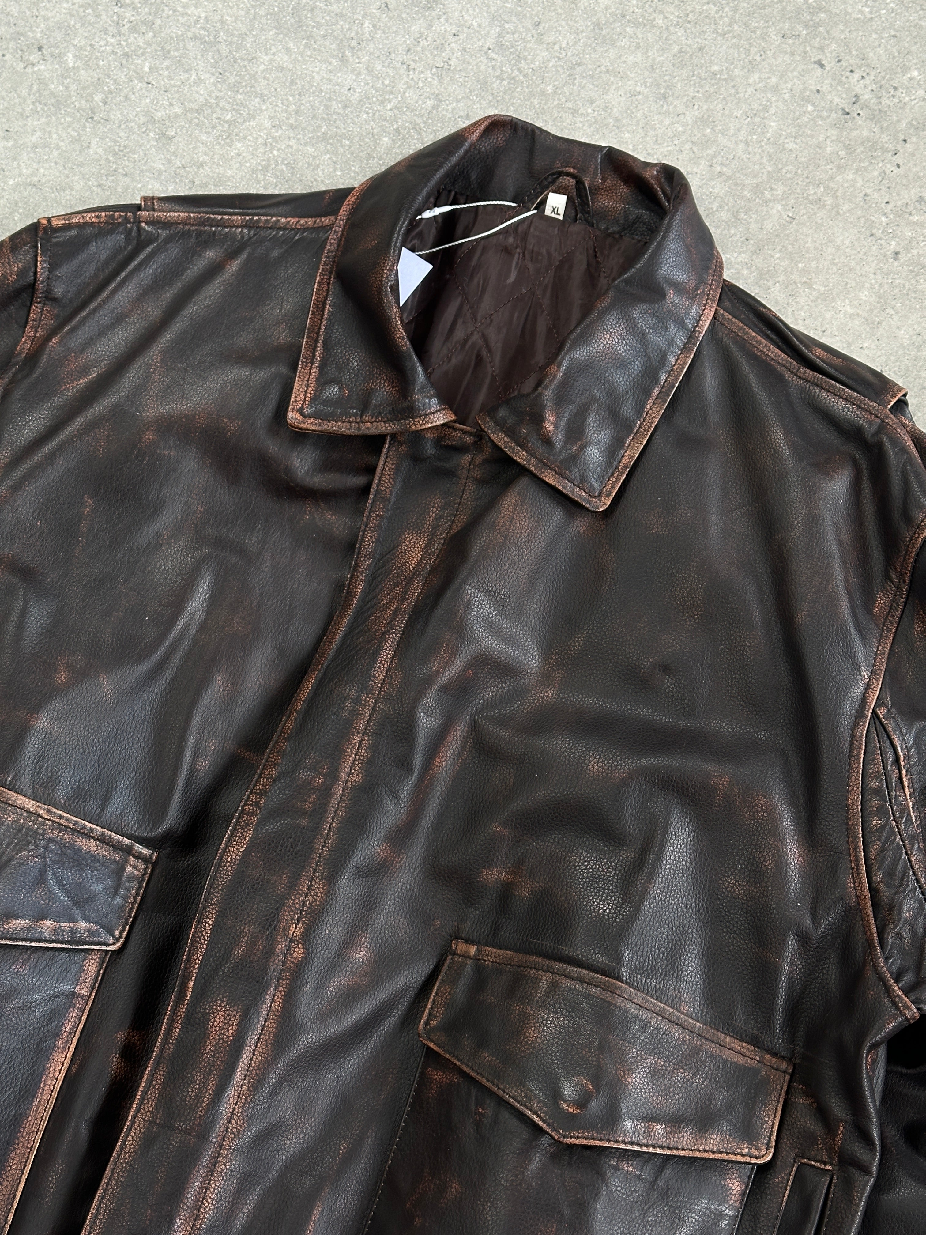 Vintage distressed leather jacket in XL size, featuring rugged design and classic style, shown on a hanger.