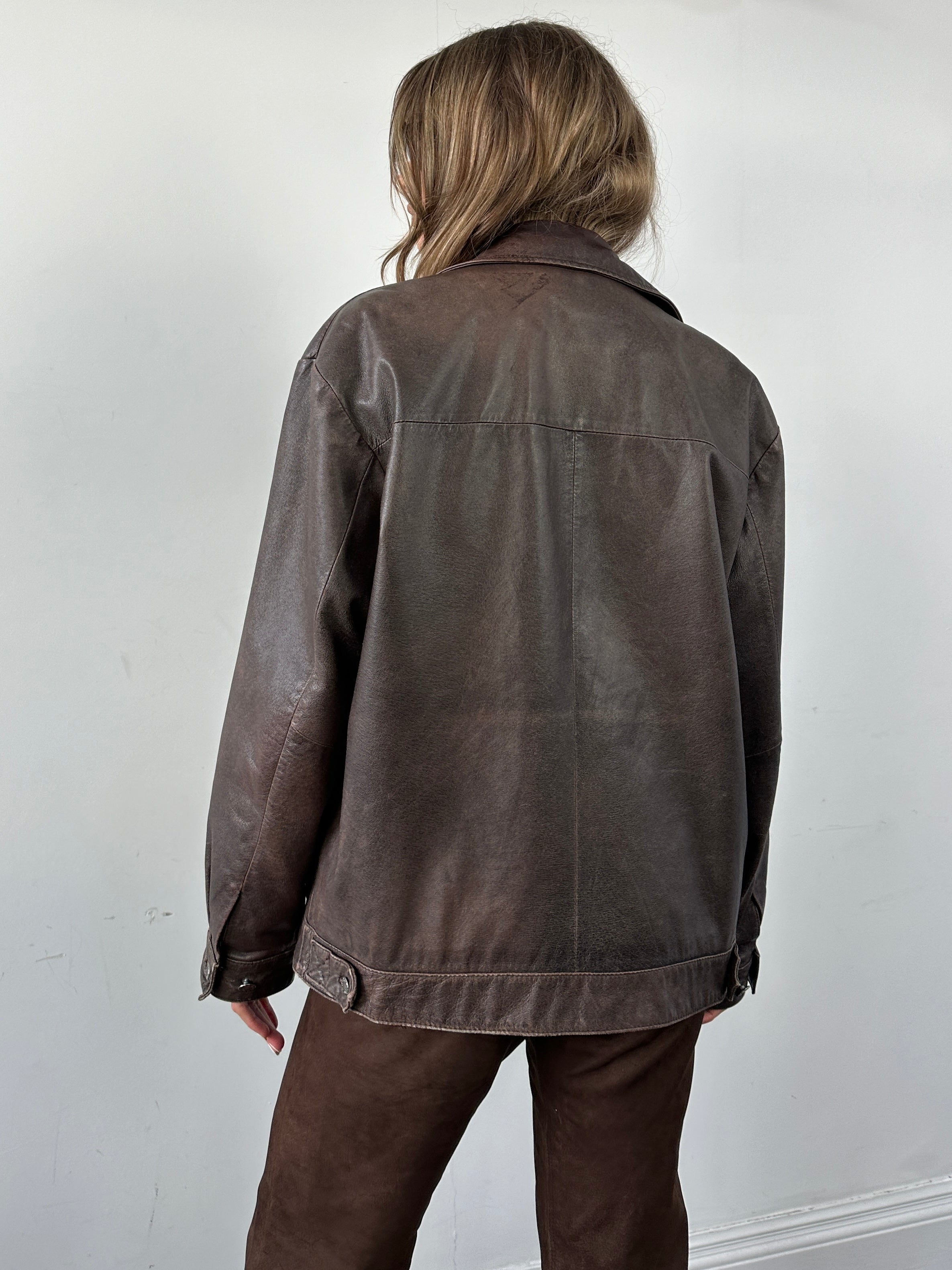 Vintage distressed leather jacket in M/L size, featuring rugged texture and classic style, shown on a hanger.