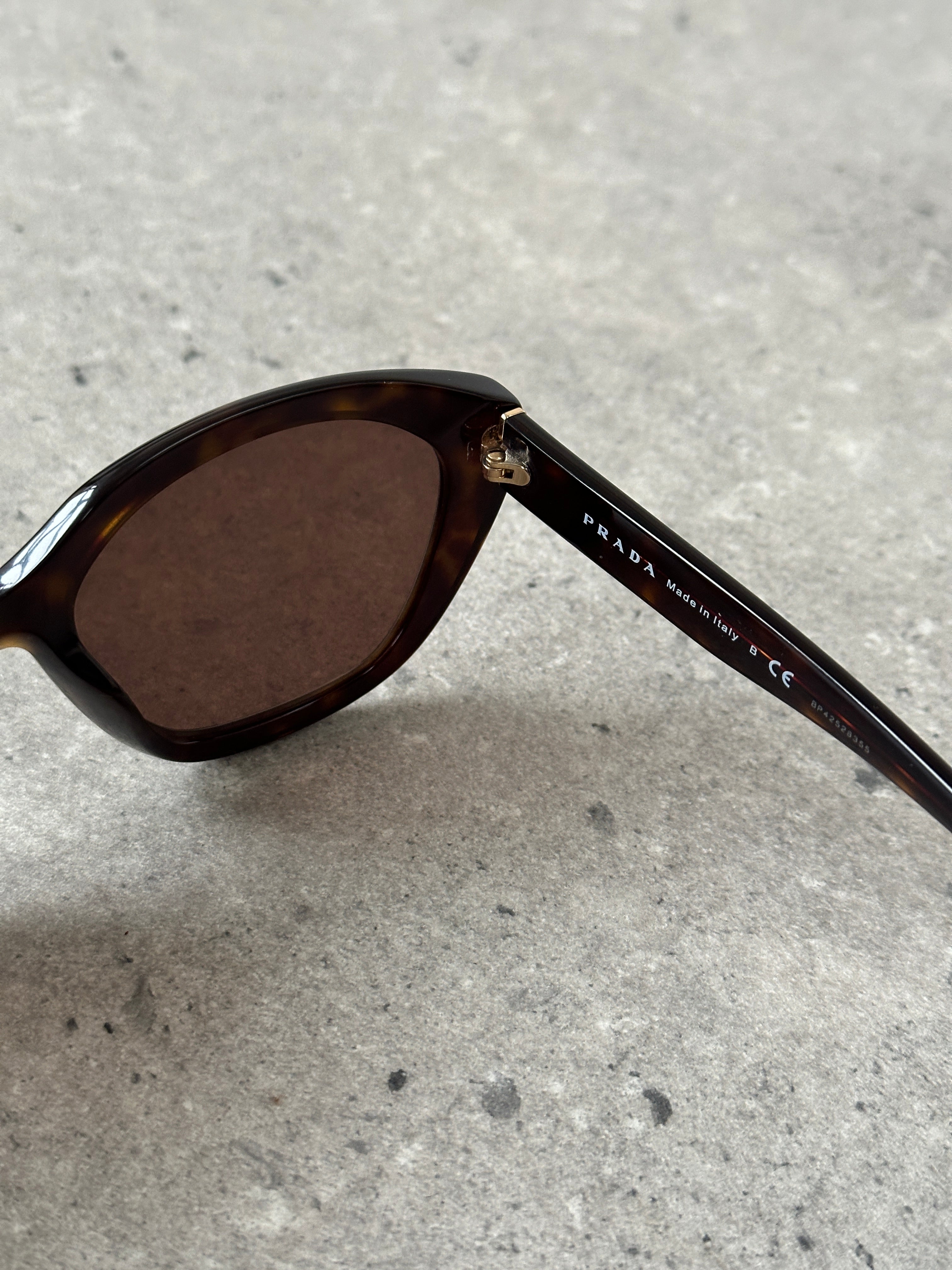Prada tortoise shell round logo sunglasses with dark tinted lenses and classic frame design.