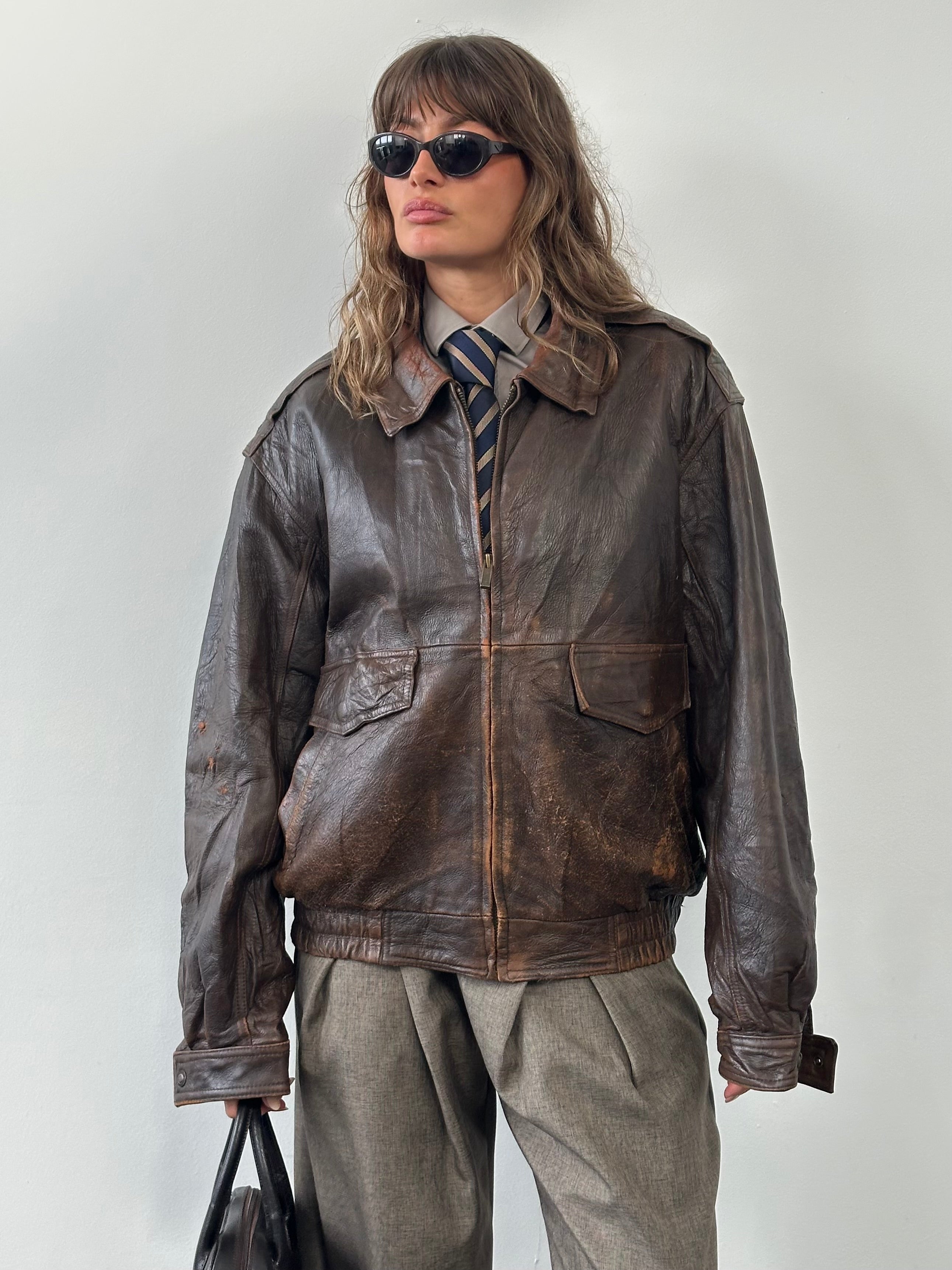 Vintage 1990s distressed leather bomber jacket in size XL, featuring a rugged, worn-in look and classic bomber style.
