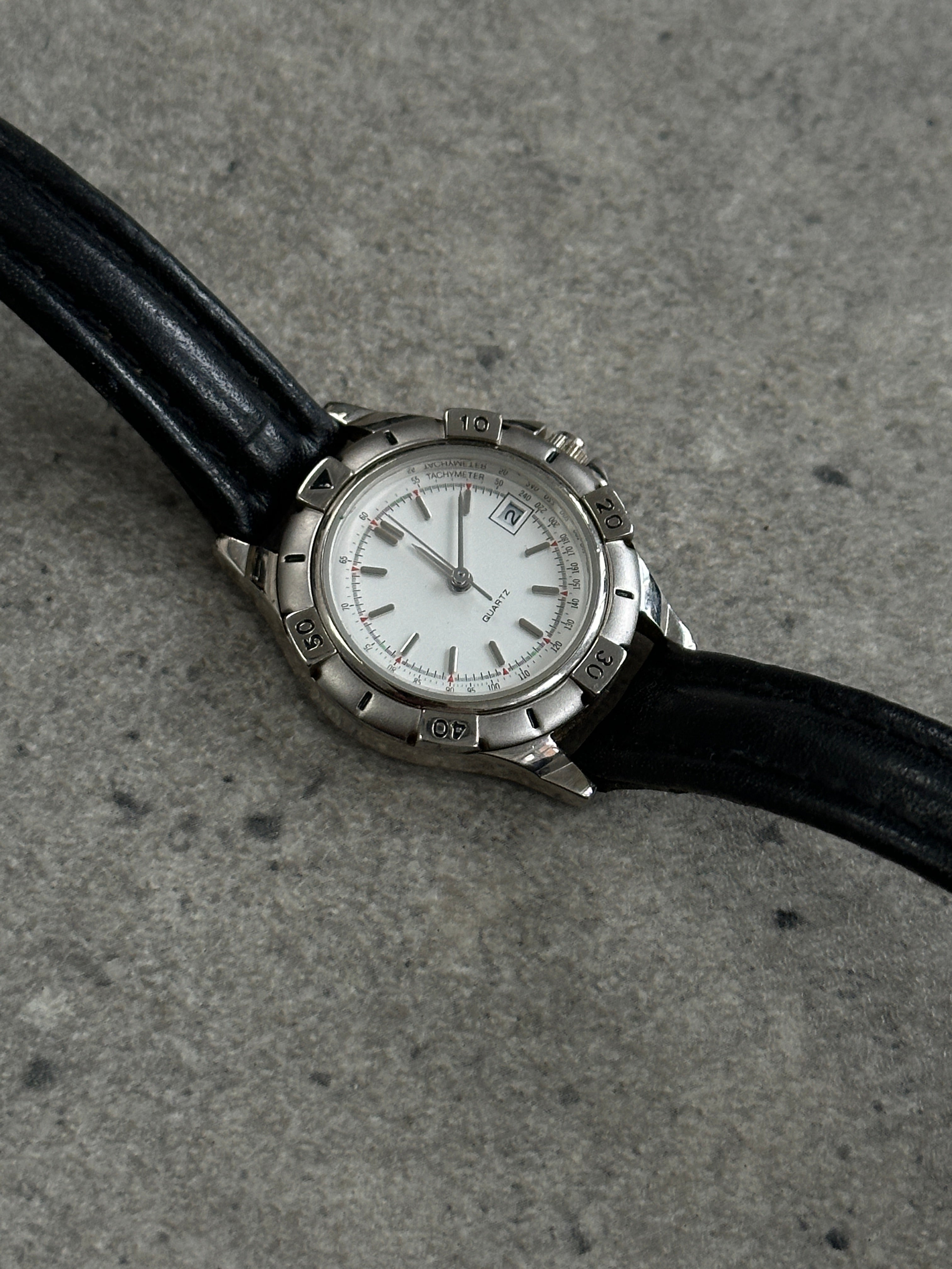 Vintage 1990s silver tone quartz watch with round dial and Japan movement, featuring a classic retro design.