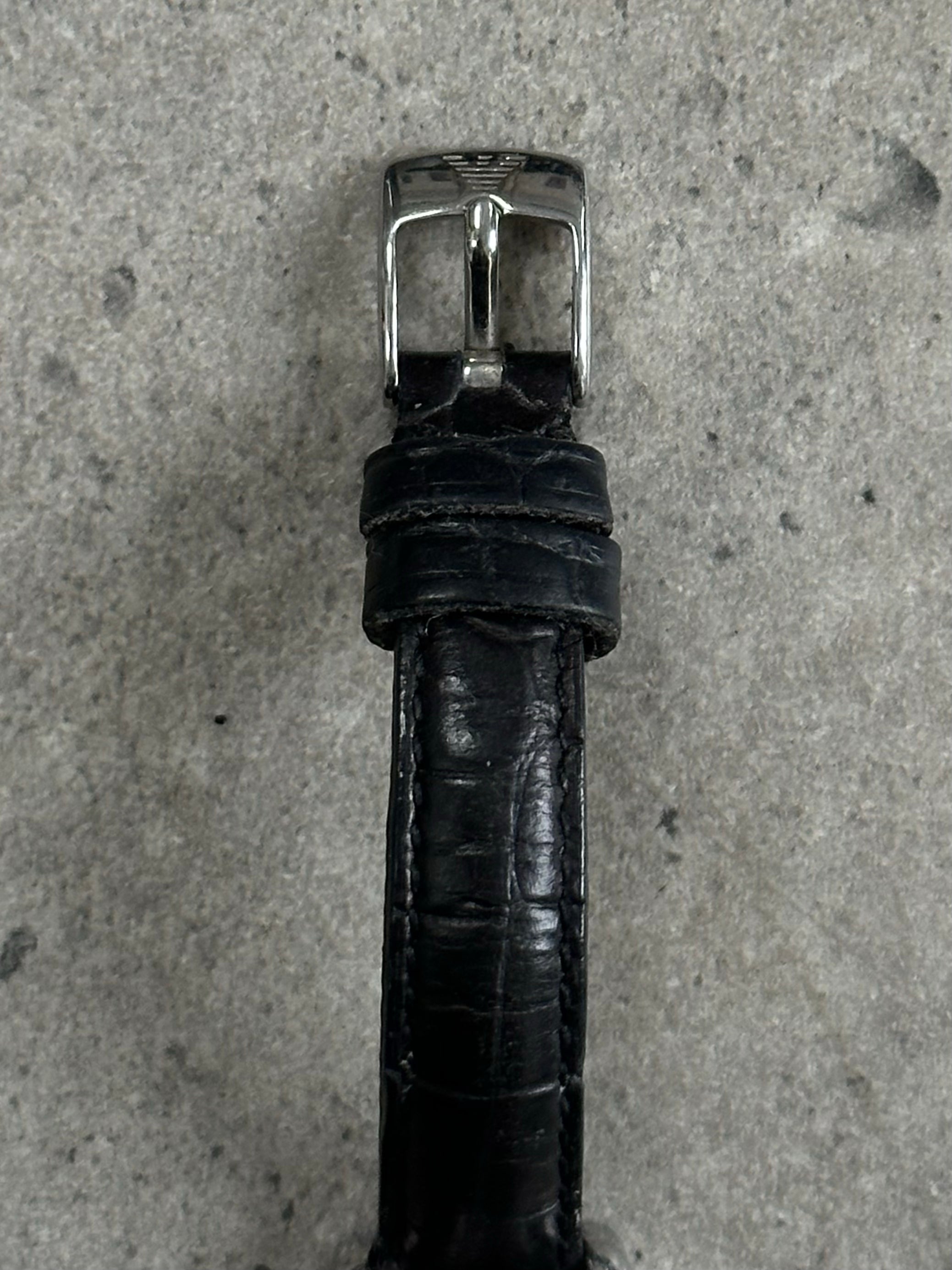 Emporio Armani 2000s leather watch with silver dial, black leather strap, and minimalist design, close-up of wrist shot.