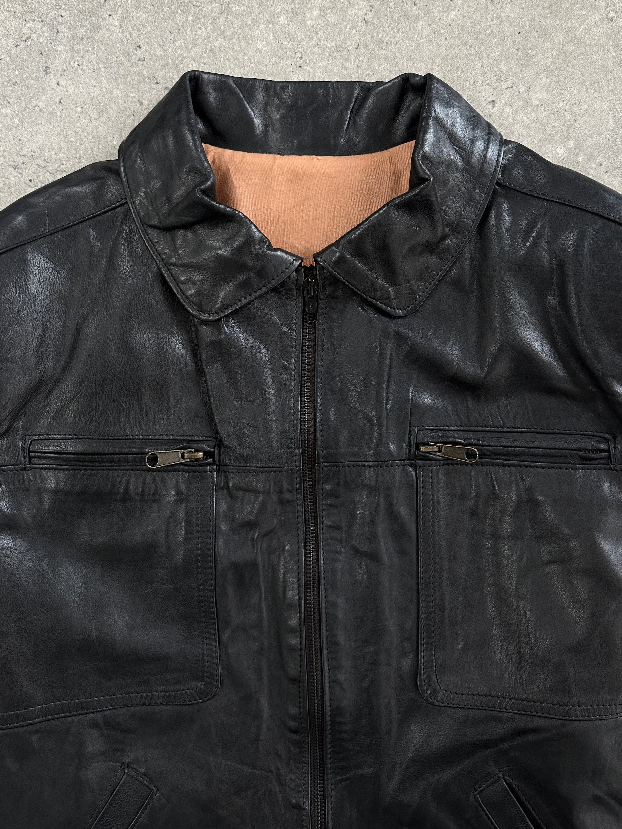 Vintage 1990s boxy cropped leather jacket in black, featuring a classic design and structured fit, displayed on a hanger.