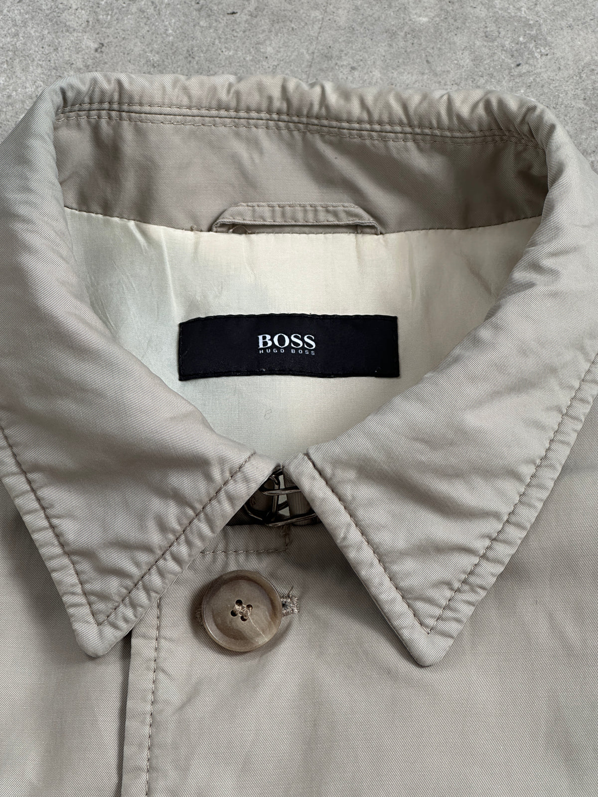 Hugo Boss 2000s high neck belted trench coat in beige, displayed on a hanger with a classic design and belted waist.