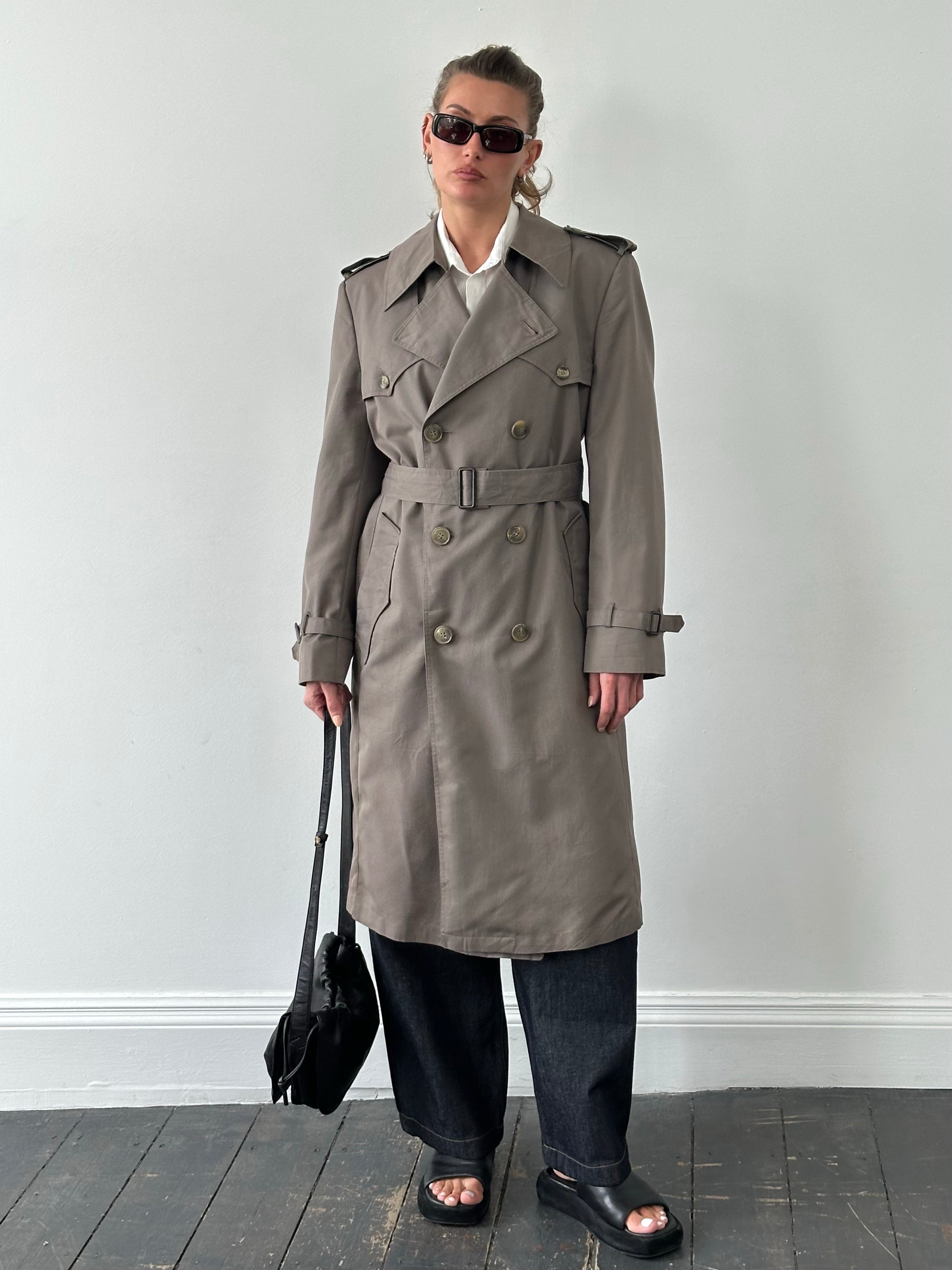 Christian Dior Monsieur 1980s double-breasted belted trench coat displayed on a hanger. Classic beige trench with structured design.