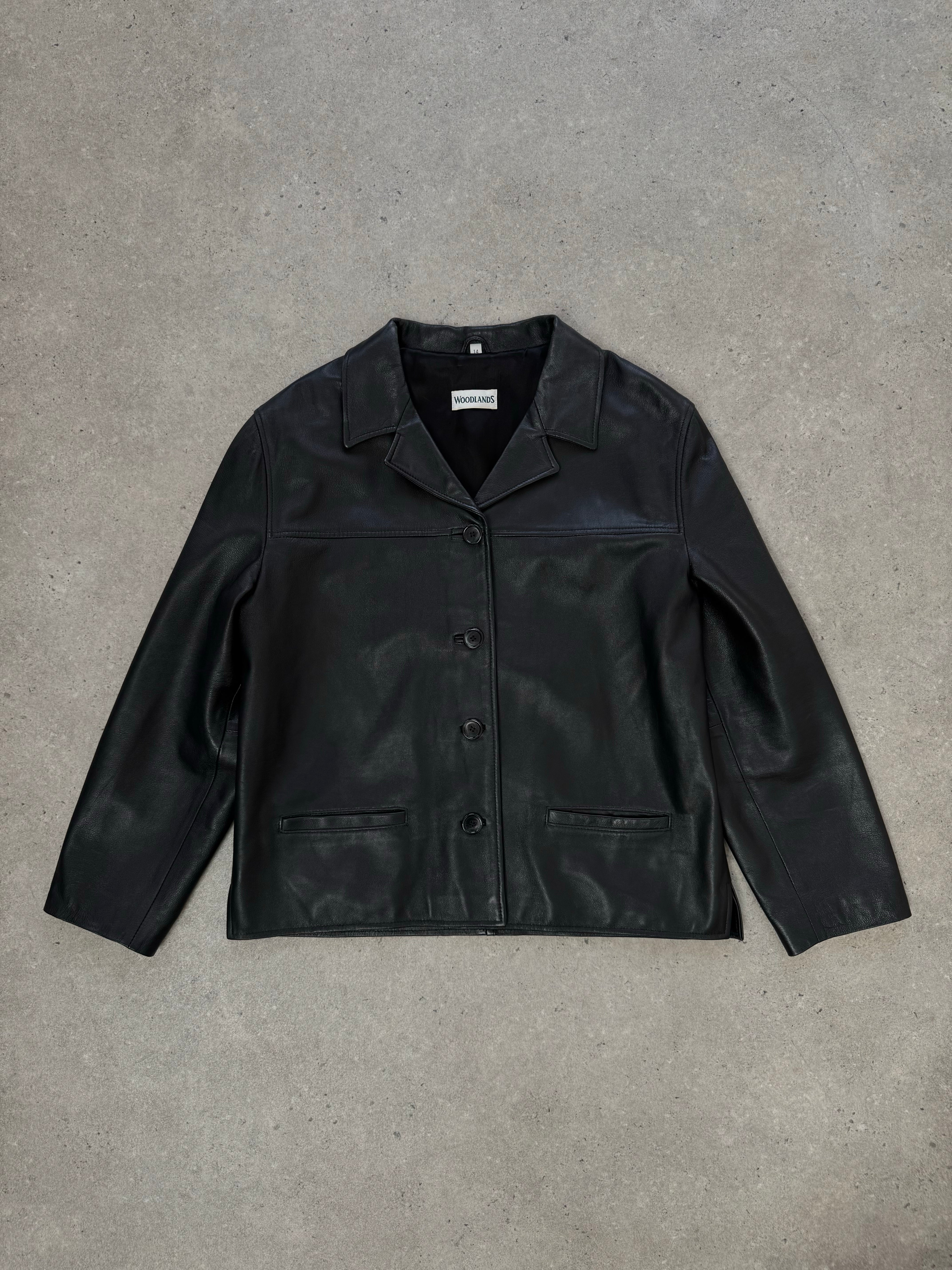 Vintage 1990s boxy leather jacket in black, featuring a classic collar and metal zipper, displayed on a hanger.
