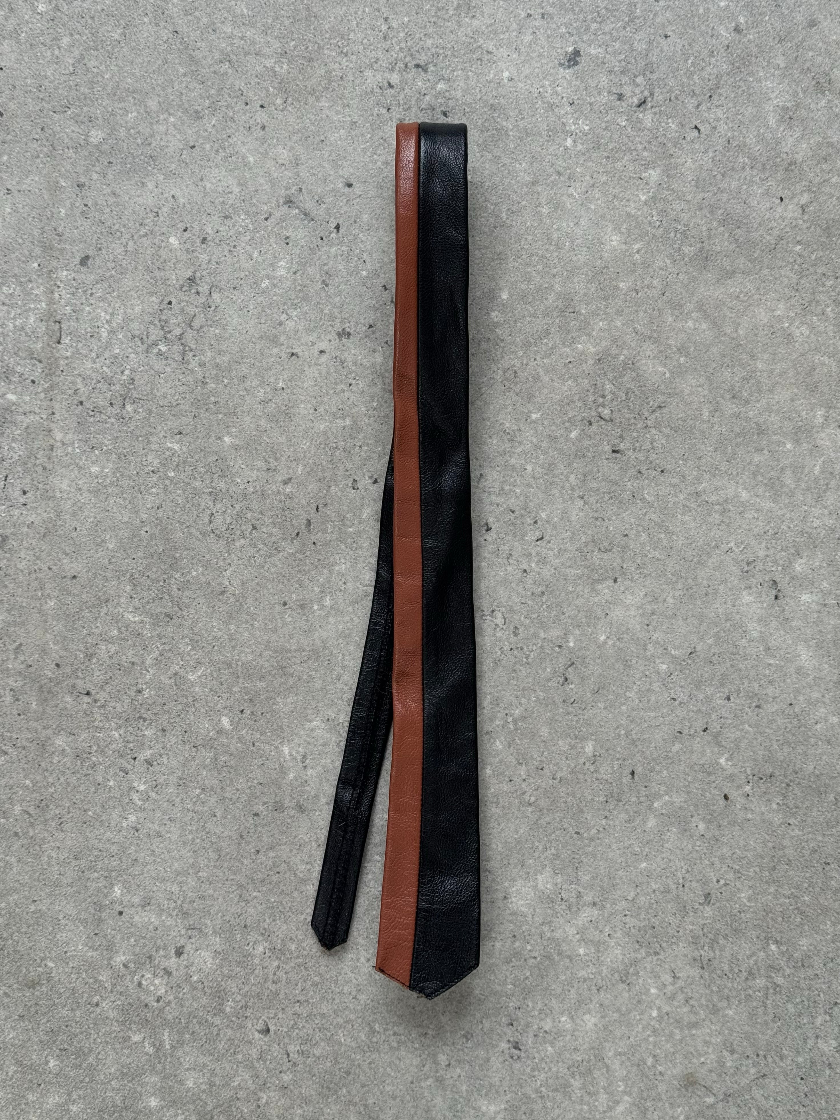 Vintage 2000s two-tone leather skinny tie with sleek design, featuring contrasting colors and narrow width.
